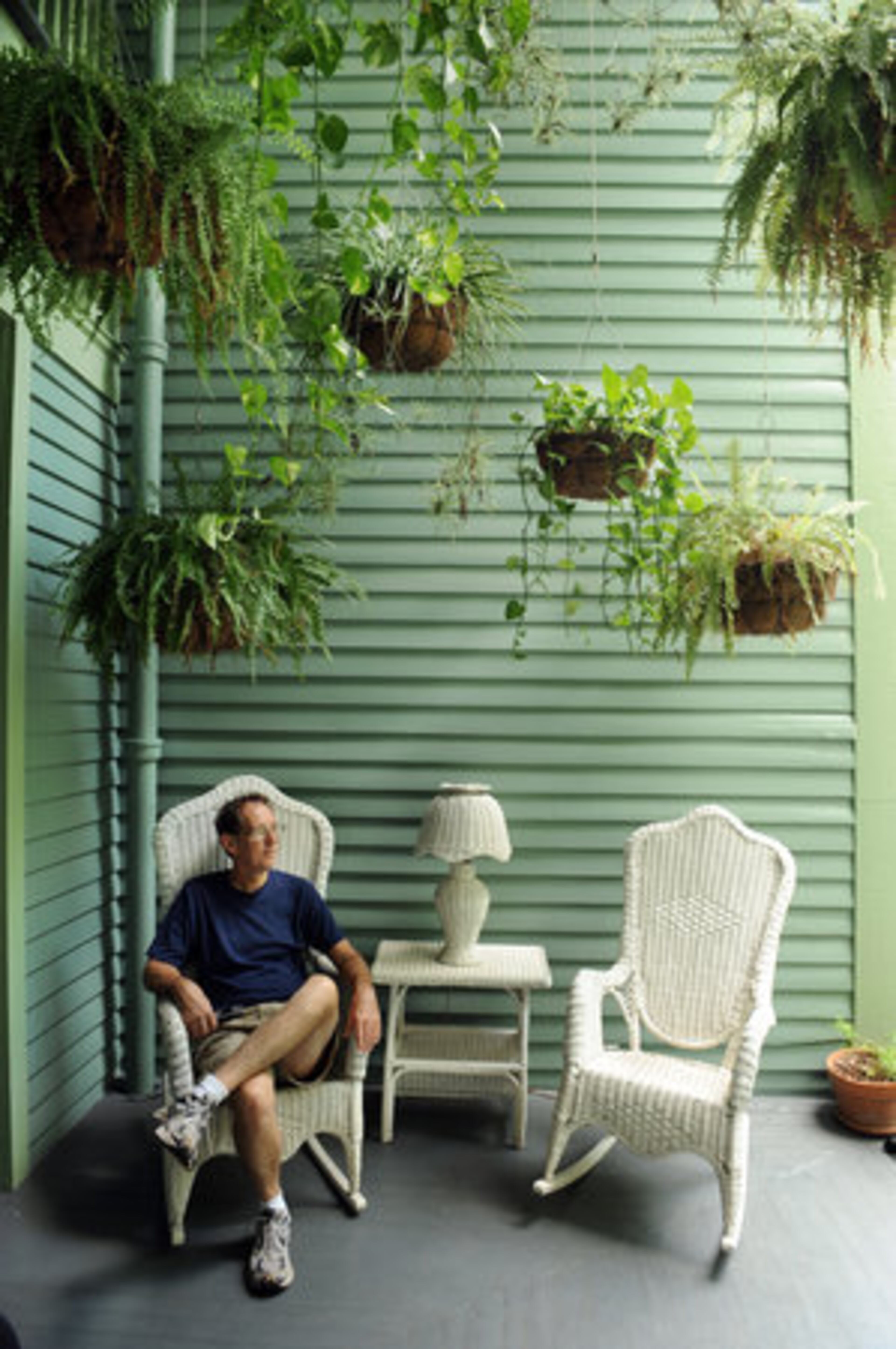 Ed McCord sits under a canopy of hanging baskets on the rear porch.