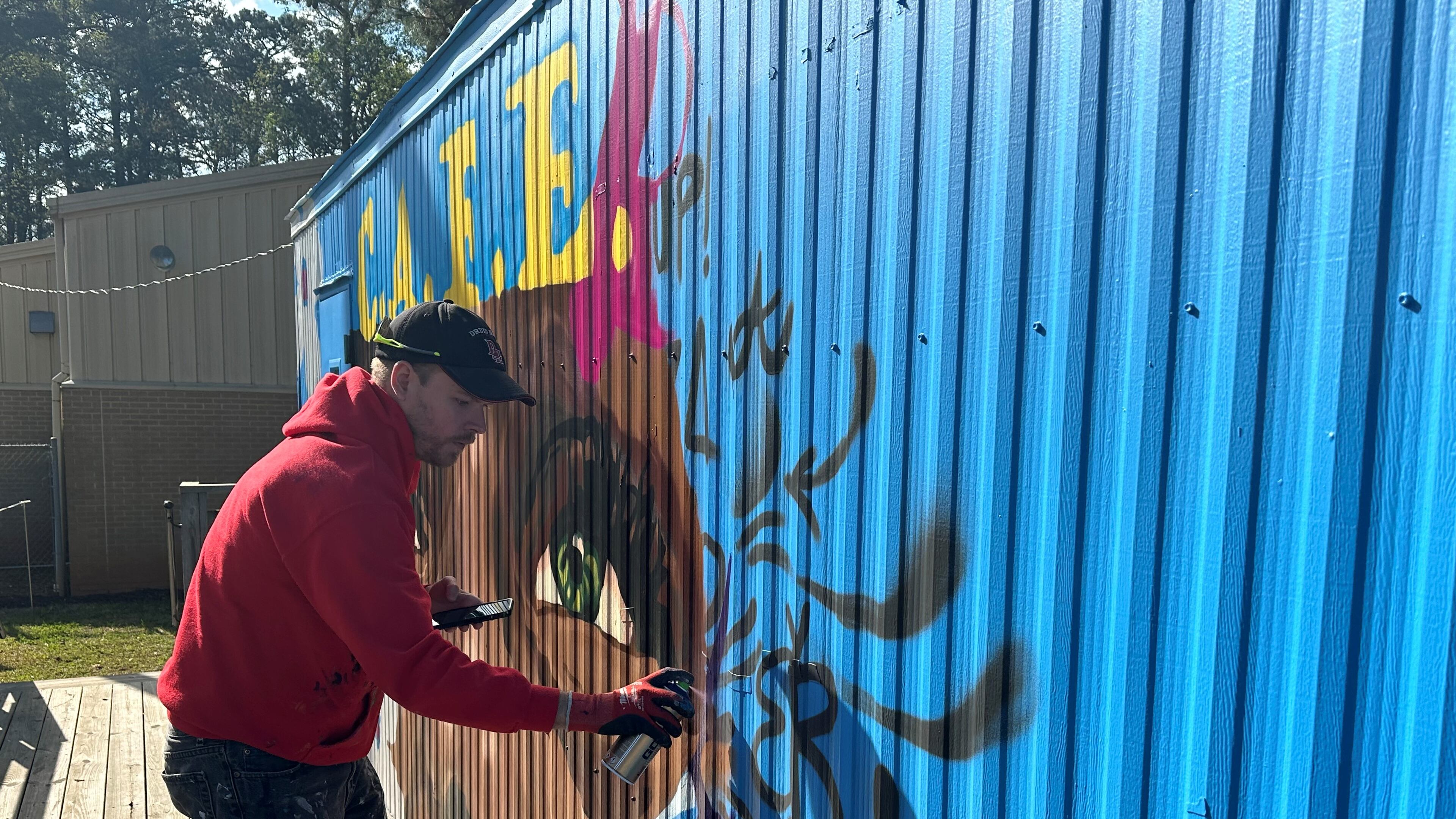 Chastain Clark, an Atlanta based muralist, designed the Dunaire C.A.F.E. Clark enjoys helping students connect with art in different ways. Students enjoy both participating in the process of mural making and seeing themselves in the finished product, he said. Nedra Rhone/nrhone@ajc.com