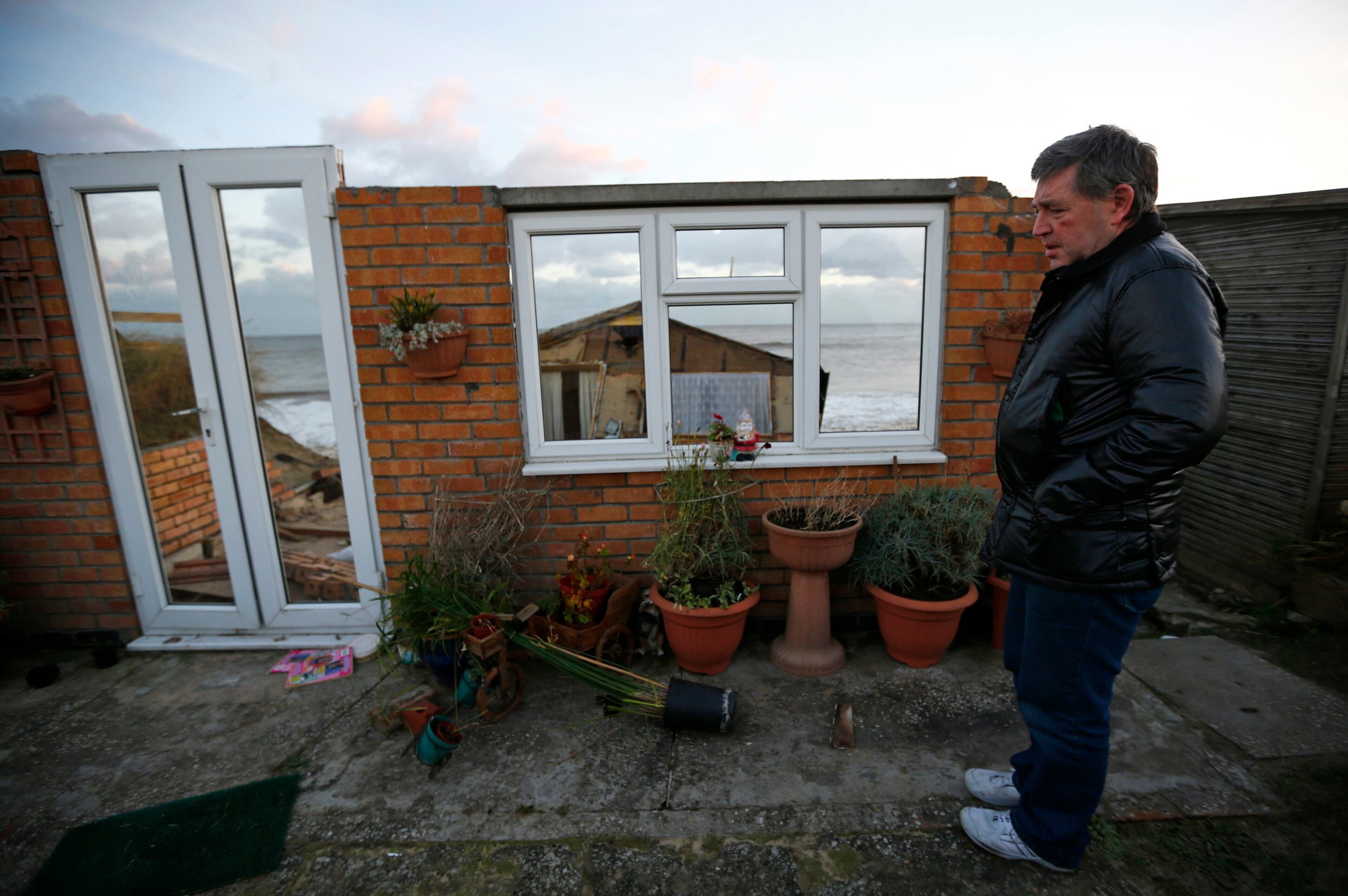 Steve Connelly looks at the remains of his home after it fell into the sea during a storm surge in Hemsby, eastern England December 6, 2013. REUTERS/Darren Staples