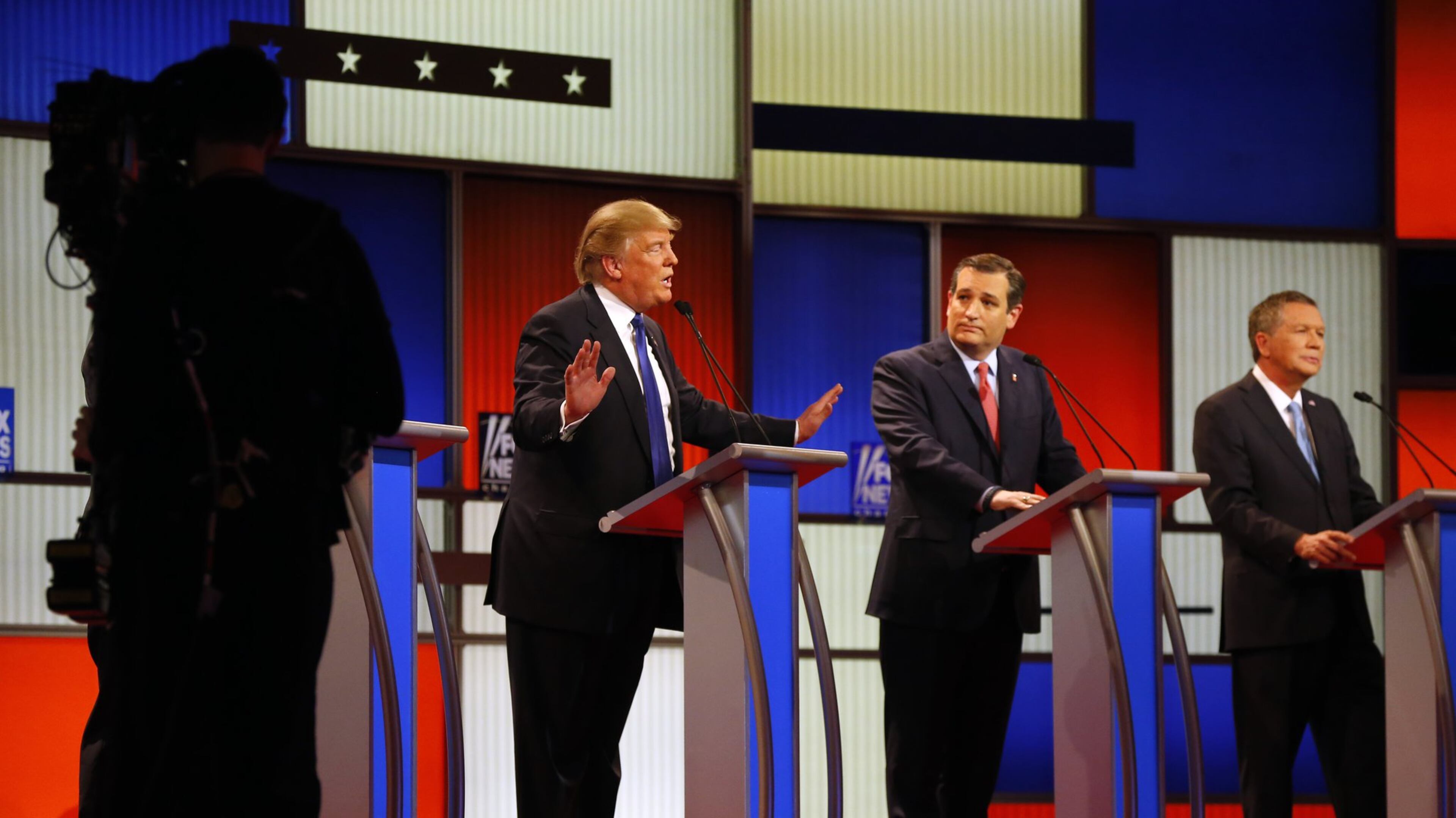 Republican presidential candidates, businessman Donald Trump, and Sen. Ted Cruz, R-Texas, argue as Ohio Gov. John Kasich listens during a Republican presidential primary debate at Fox Theatre, Thursday, March 3, 2016, in Detroit. (AP Photo/Paul Sancya)