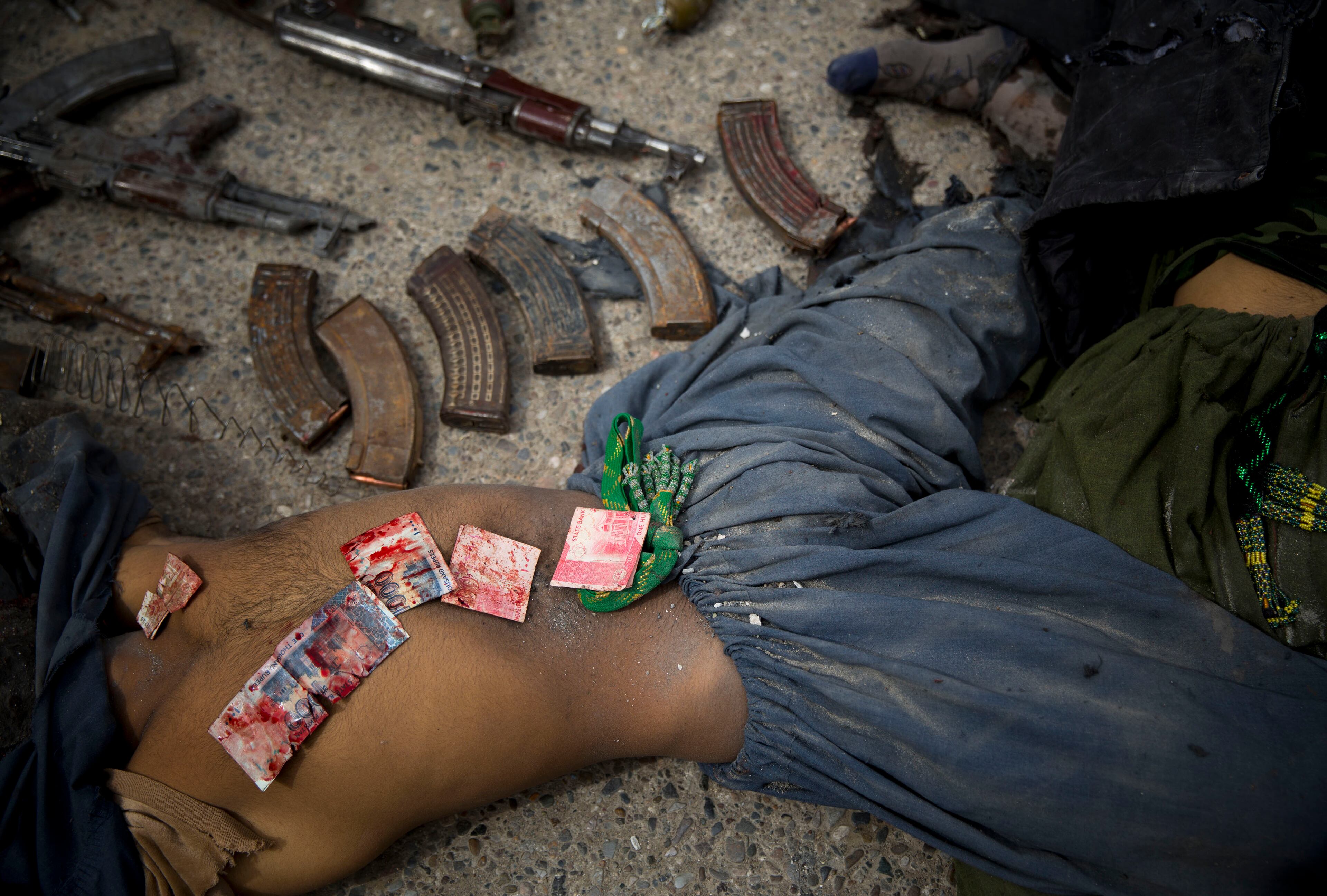 In this Wednesday, March 12, 2014 file photo made by Associated Press photographer Anja Niedringhaus, Pakistani bank notes covered in blood are displayed on the body of a dead suicide bomber after police found them in his pocket after an attack on the former Afghan intelligence headquarters, in the center of Kandahar, Afghanistan. Niedringhaus, 48, an internationally acclaimed German photographer, was killed and AP reporter Kathy Gannon was wounded on Friday, April 4, 2014 when an Afghan policeman opened fire while they were sitting in their car in eastern Afghanistan. (AP Photo/Anja Niedringhaus, File)