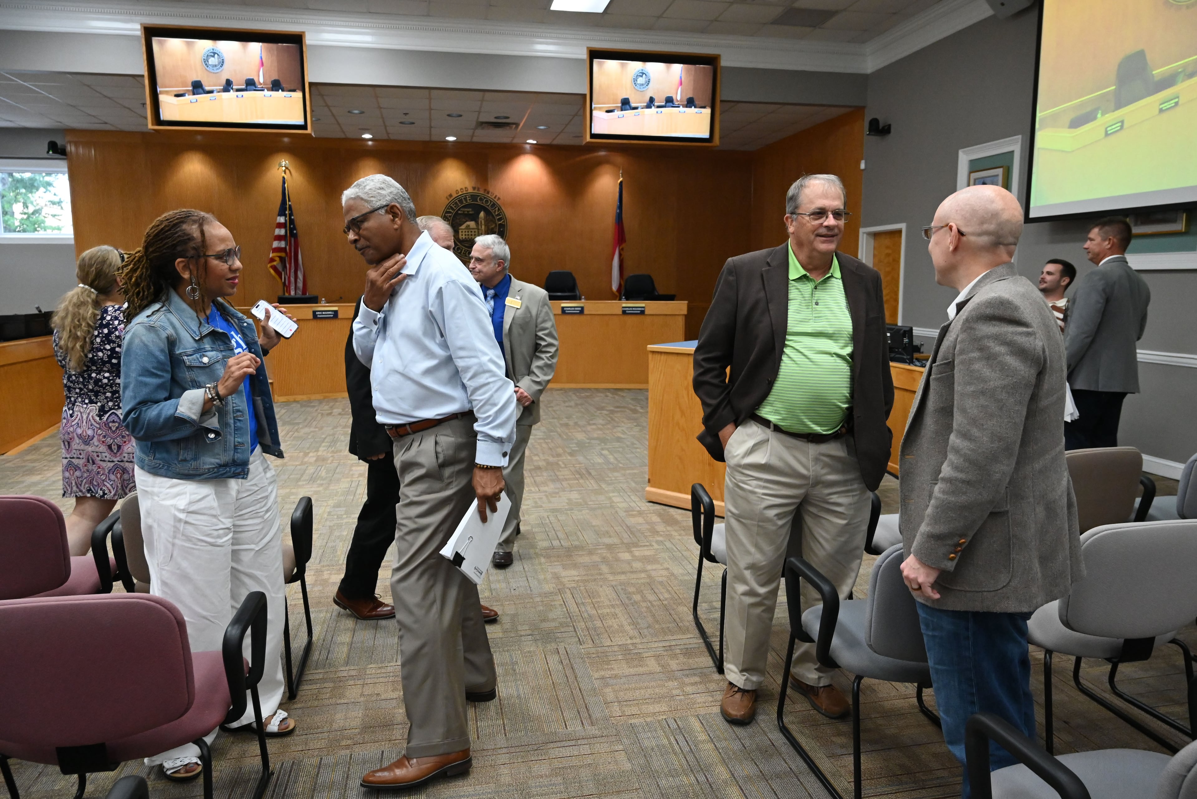 Fayette County Commissioner Charles Rousseau (center left) and Chairman Lee Hearn (center right, in green shirt) speak with attendees at a commission meeting Thursday, Aug. 13, 2026, in Fayetteville. (Hyosub Shin/AJC)