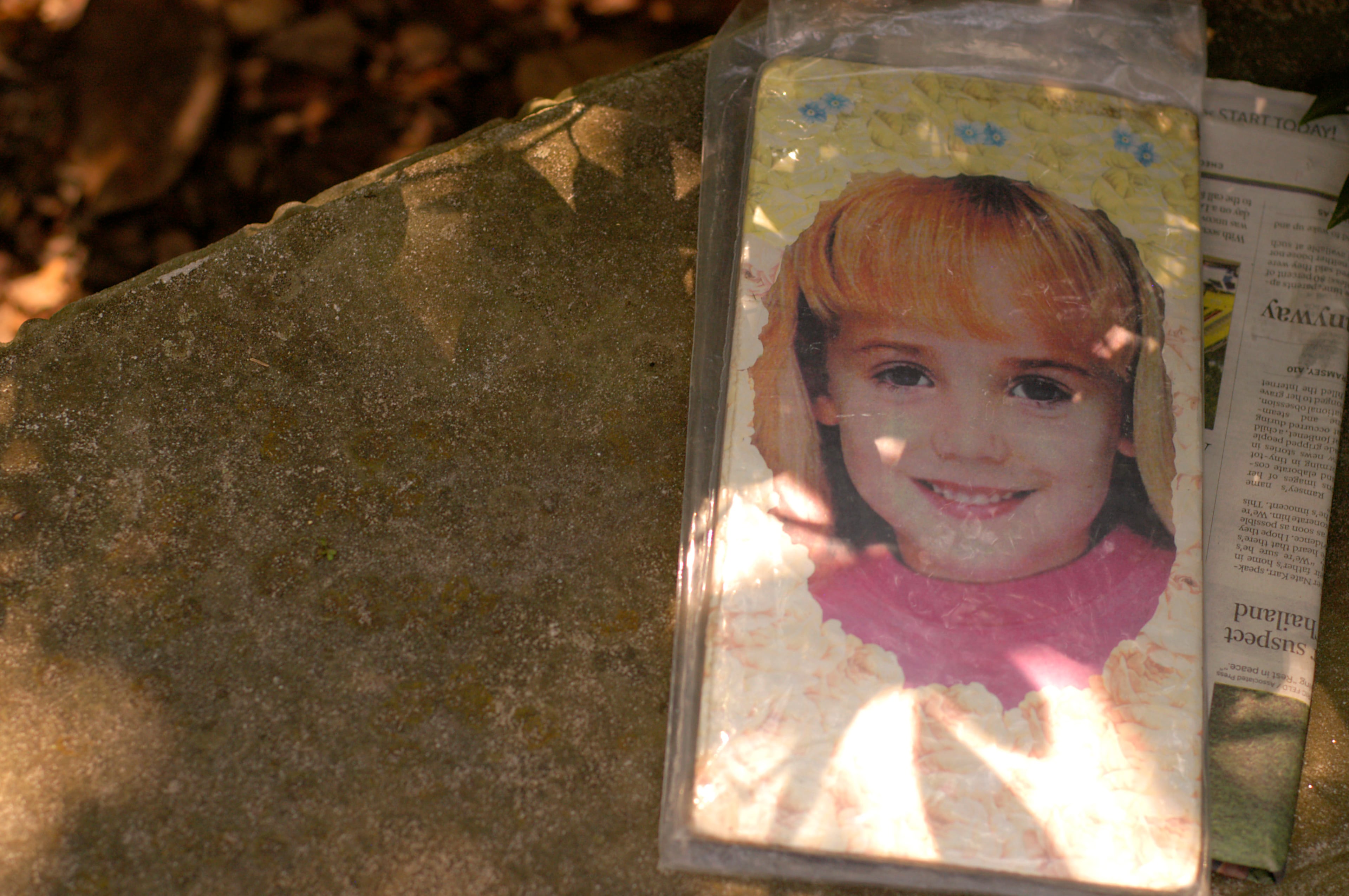 A photo from a newspaper of JonBenet rests on a bench near her grave site at St. James Cemetery in Marietta. JonBenet would be 23 years old now.