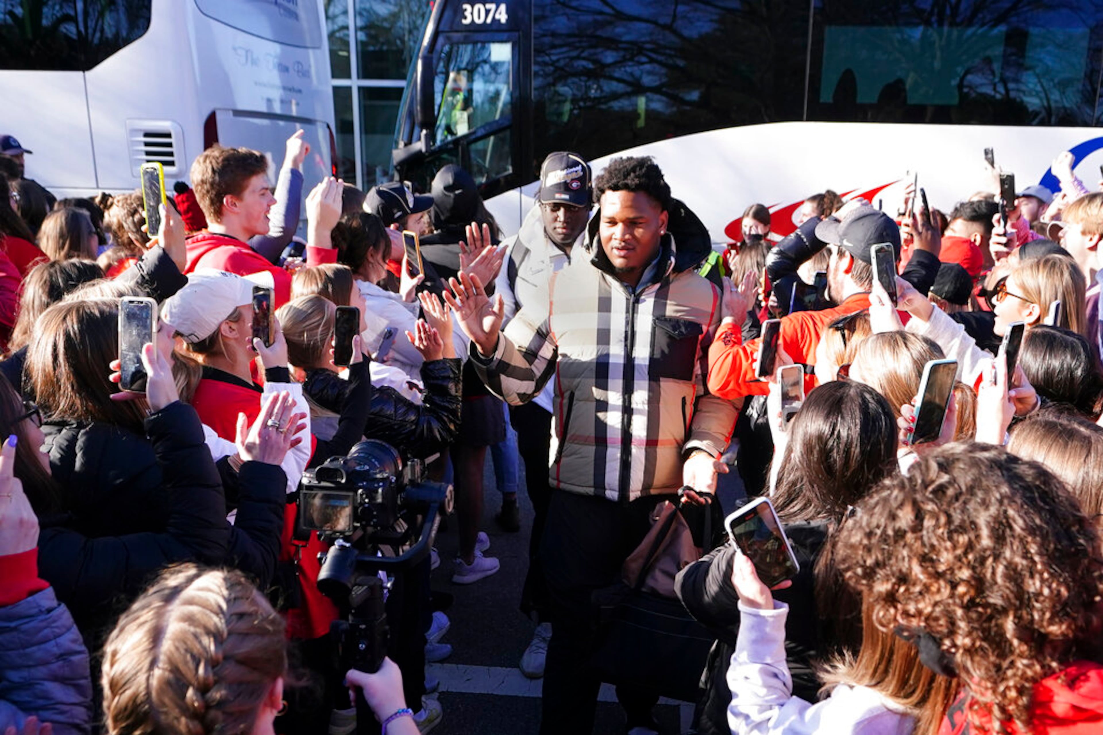 Georgia players are greeted by a large crowd of fans as they return to the Georgia campus, Tuesday, Jan. 11, 2022, in Athens, Ga., after defeating Alabama in the College Football Championship NCAA college football game. (AP Photo/John Bazemore)