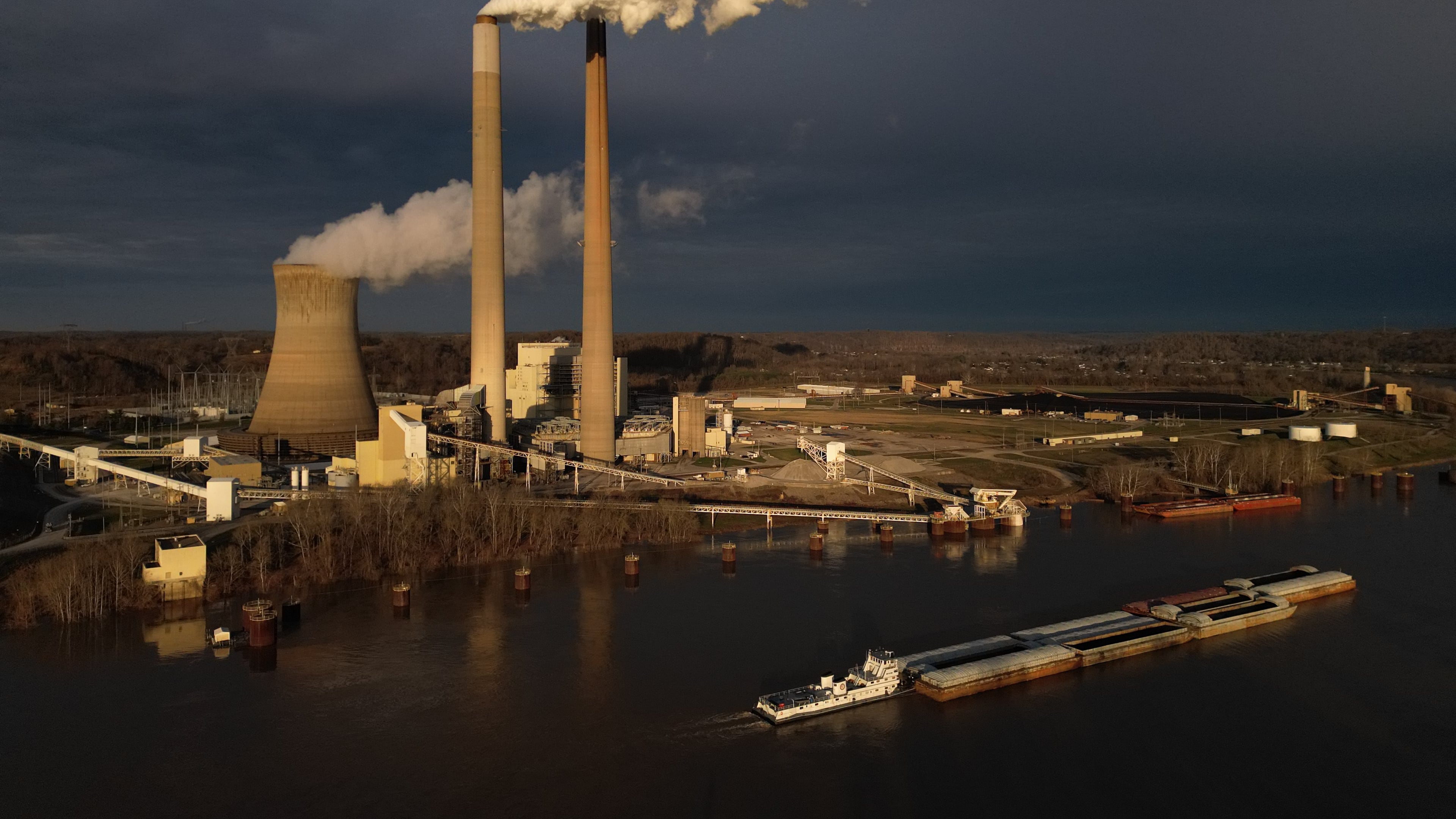FILE - A barge on the Ohio River moves past the Mountaineer Power Plant, a coal-fired power plant near New Haven, W.Va., March 13, 2026. (AP Photo/Carolyn Kaster, File)