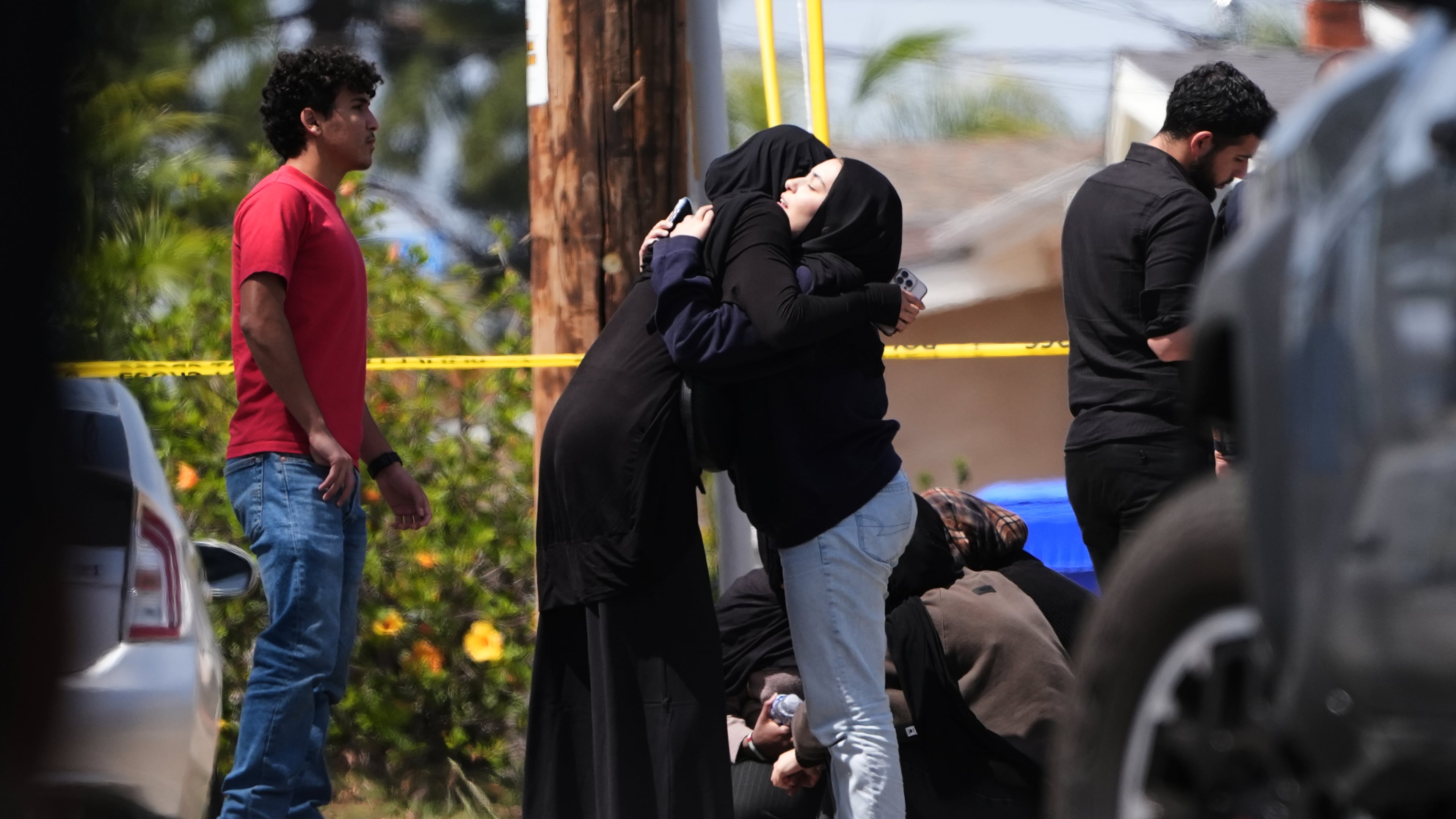 FILE - People embrace near the scene of a shooting outside the Islamic Center in San Diego, May 18, 2026, (AP Photo/Gregory Bull, File)
