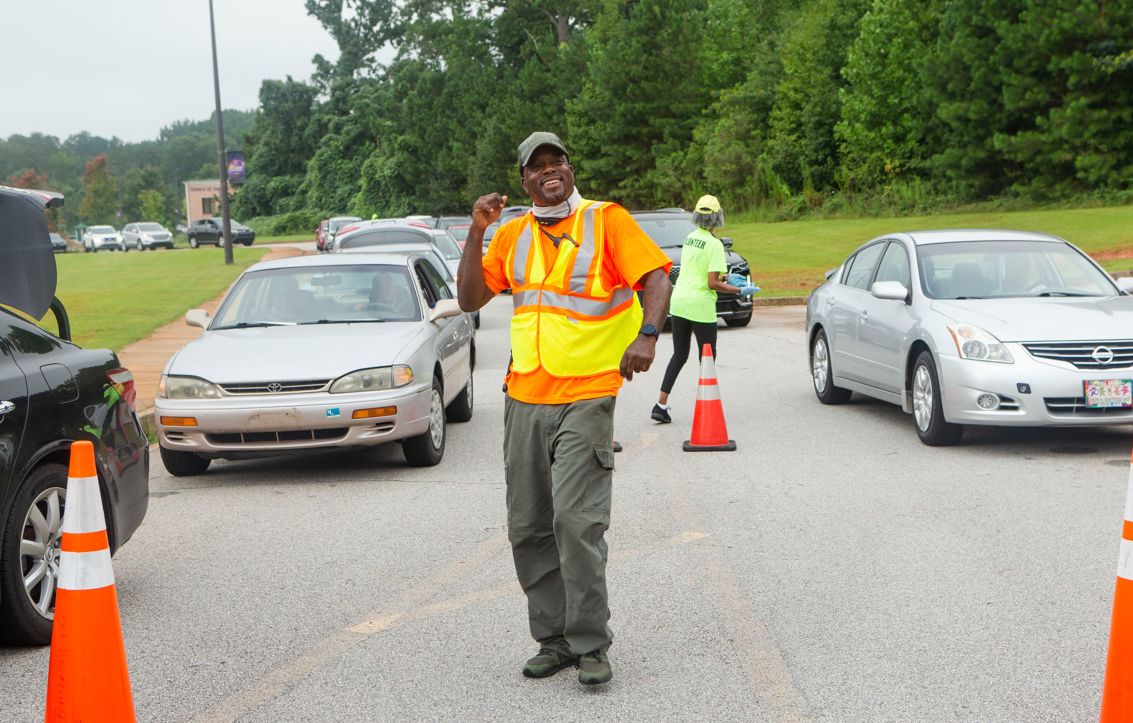 Ryan Watkins dances and directs traffic while volunteering during a food giveaway event at Berean Christian Church on Saturday, August 27, 2022, in Stone Mountain. The free food was paid for using federal COVID-19 stimulus funds, and was distributed at churches throughout DeKalb County. CHRISTINA MATACOTTA FOR THE ATLANTA JOURNAL-CONSTITUTION.