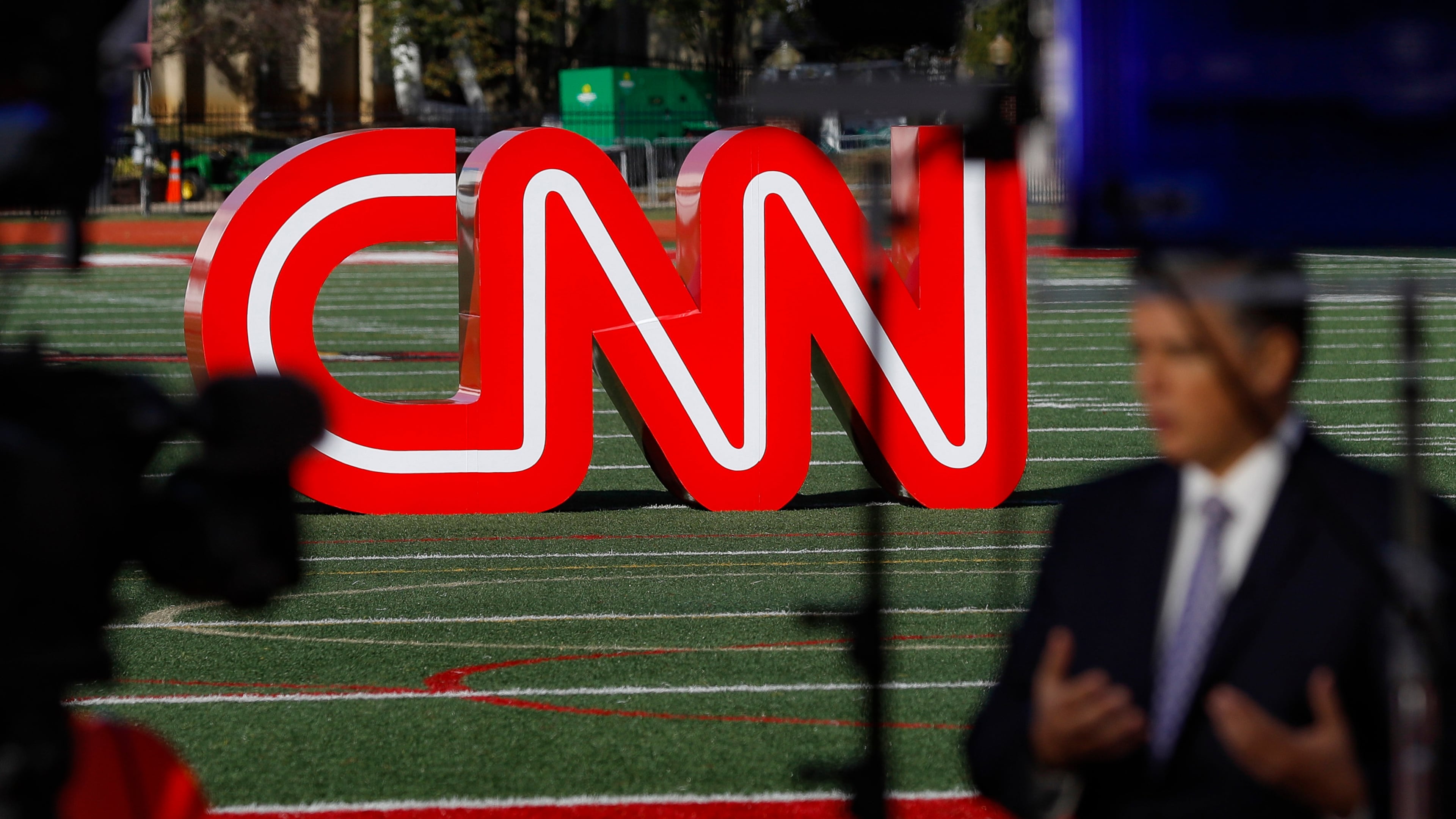 FILE - A journalist records video near a CNN sign on an athletic field outside the Clements Recreation Center where the CNN/New York Times will host the Democratic presidential primary debate at Otterbein University, Monday, Oct. 14, 2019, in Westerville, Ohio. (AP Photo/John Minchillo, File)