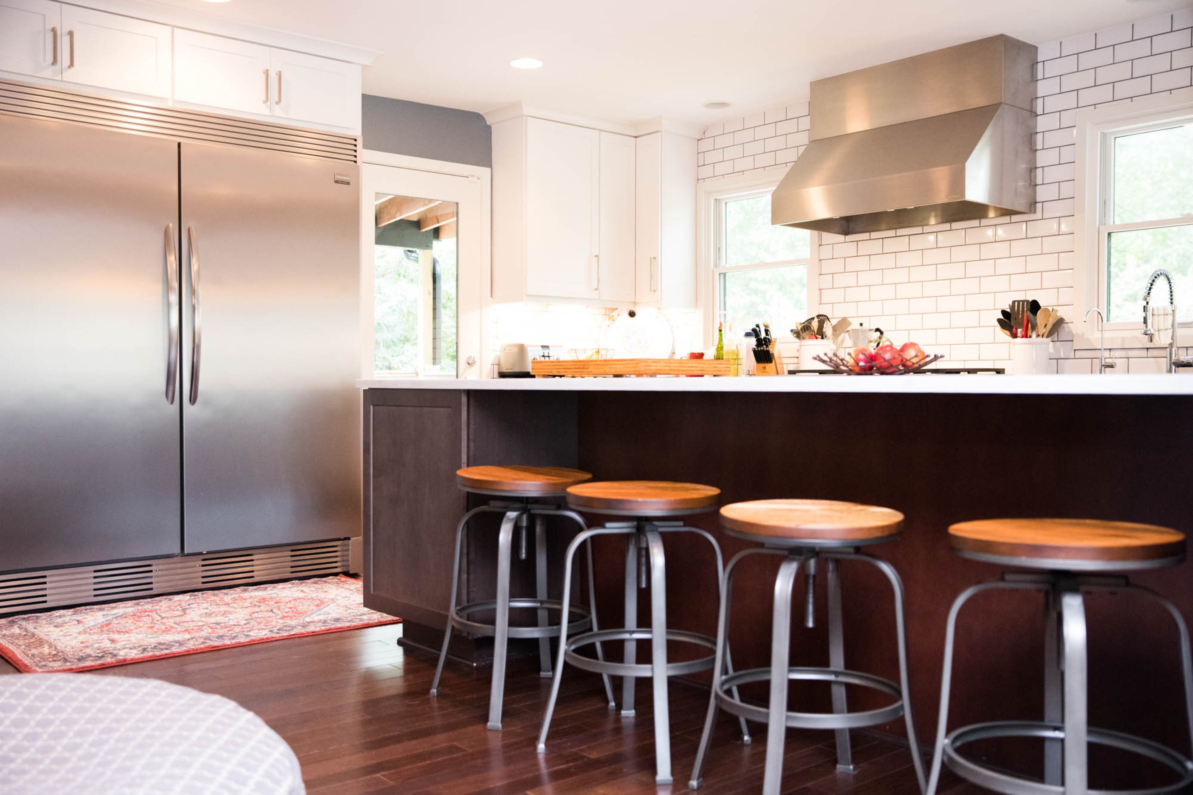 Adam Perry and Ben Ratossa have a chic transitional style in their home, but they've added in industrial touches and warm woods, like the huge Frigidaire Gallery refrigerator, the stools from Target that line their island and the exposed unfinished wood beams on the ceiling.