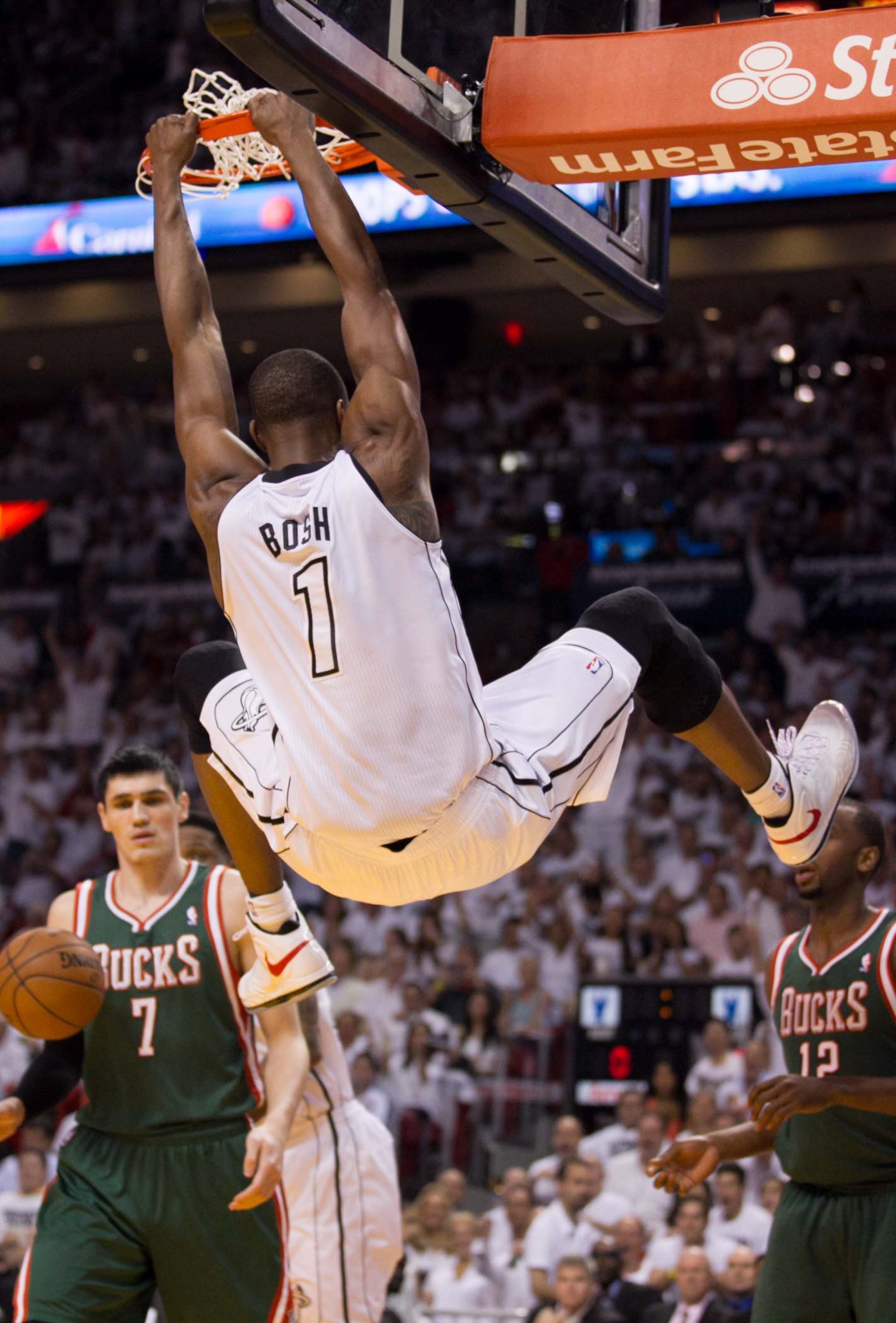Miami Heat center Chris Bosh (1) dunks over Milwaukee Bucks small forward Ersan Ilyasova (7) and Milwaukee Bucks power forward Luc Richard Mbah a Moute (12) in the first quarter at AmericanAirlines Arena on April 21, 2013. (Allen Eyestone/The Palm Beach Post)