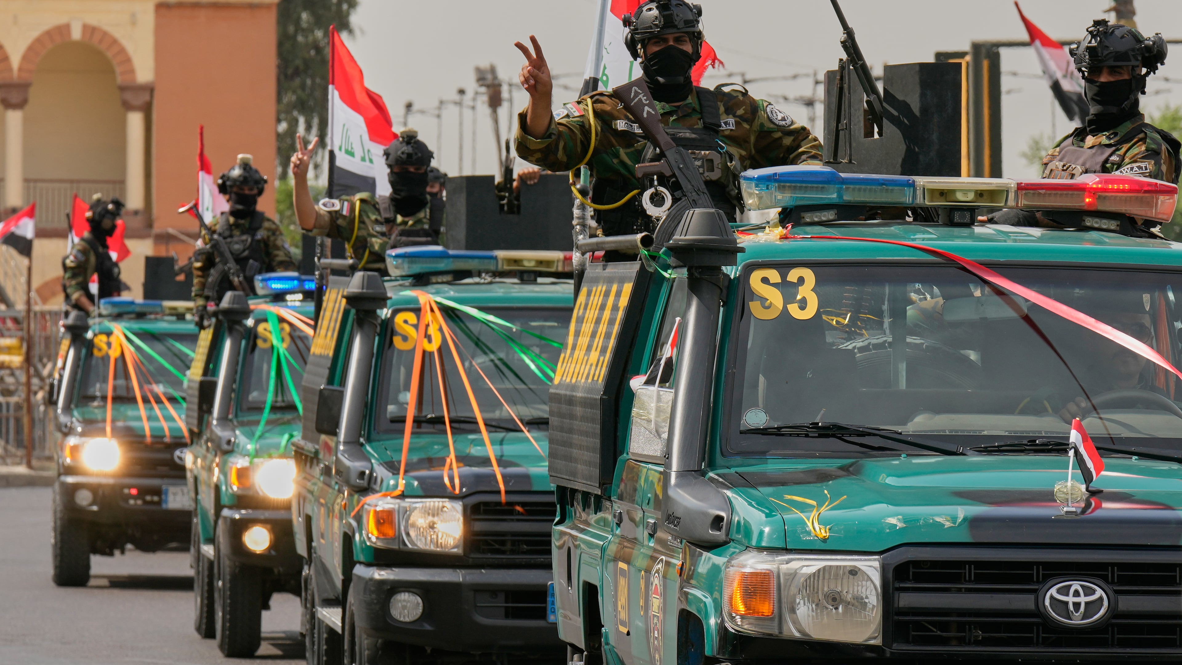 Iraqi security officers flash victory signs as they ride on vehicles decorated with national flags and ribbons during a convoy celebrating the complete withdrawal of U.S. troops from Iraq, in Baghdad, Iraq, Wednesday, Sept. 30, 2026. (AP Photo/Hadi Mizban)