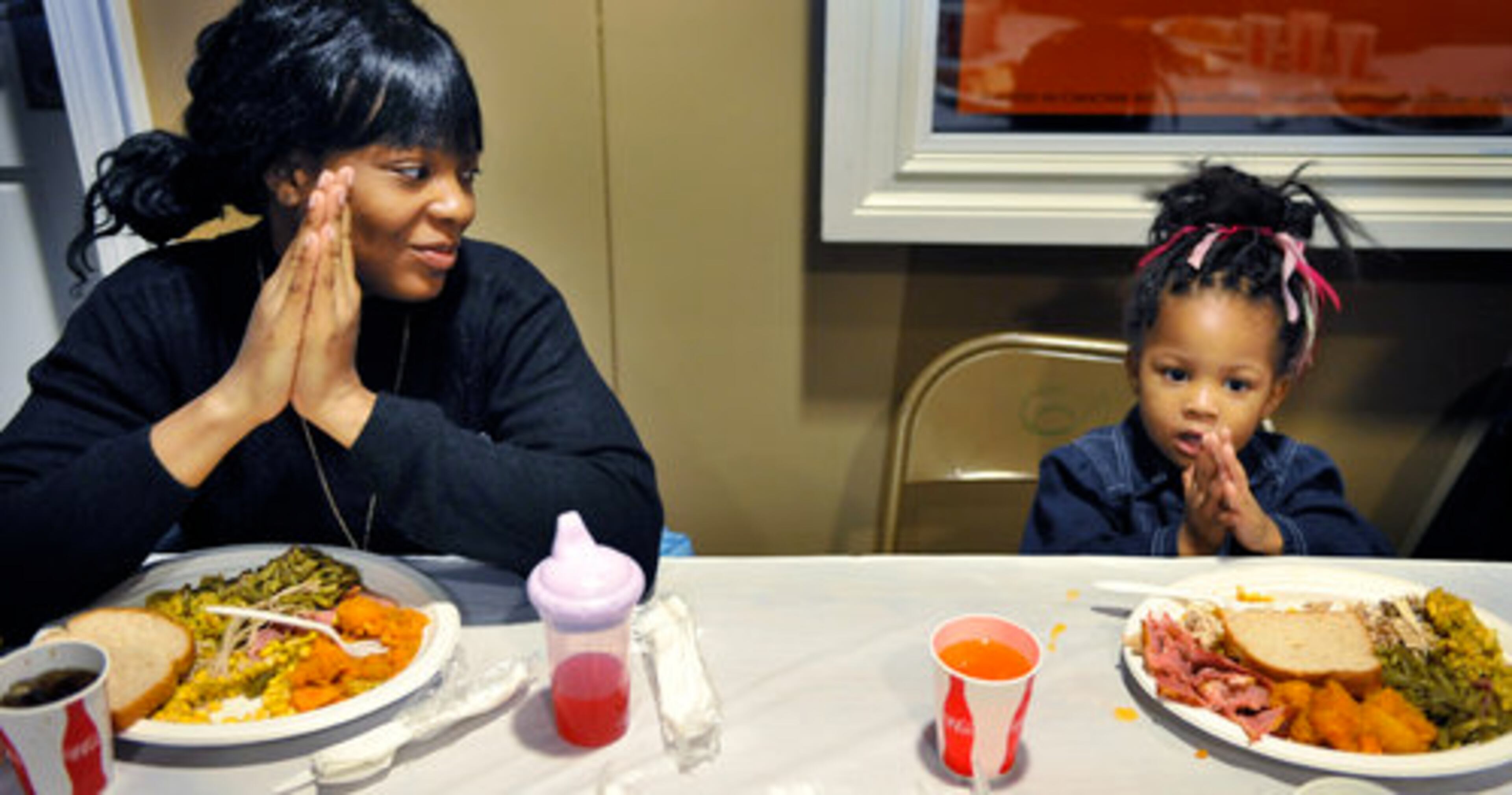 Kendra Earls and her 2-year-old daughter Aniya say a prayer before eating their Thanksgiving meal.
