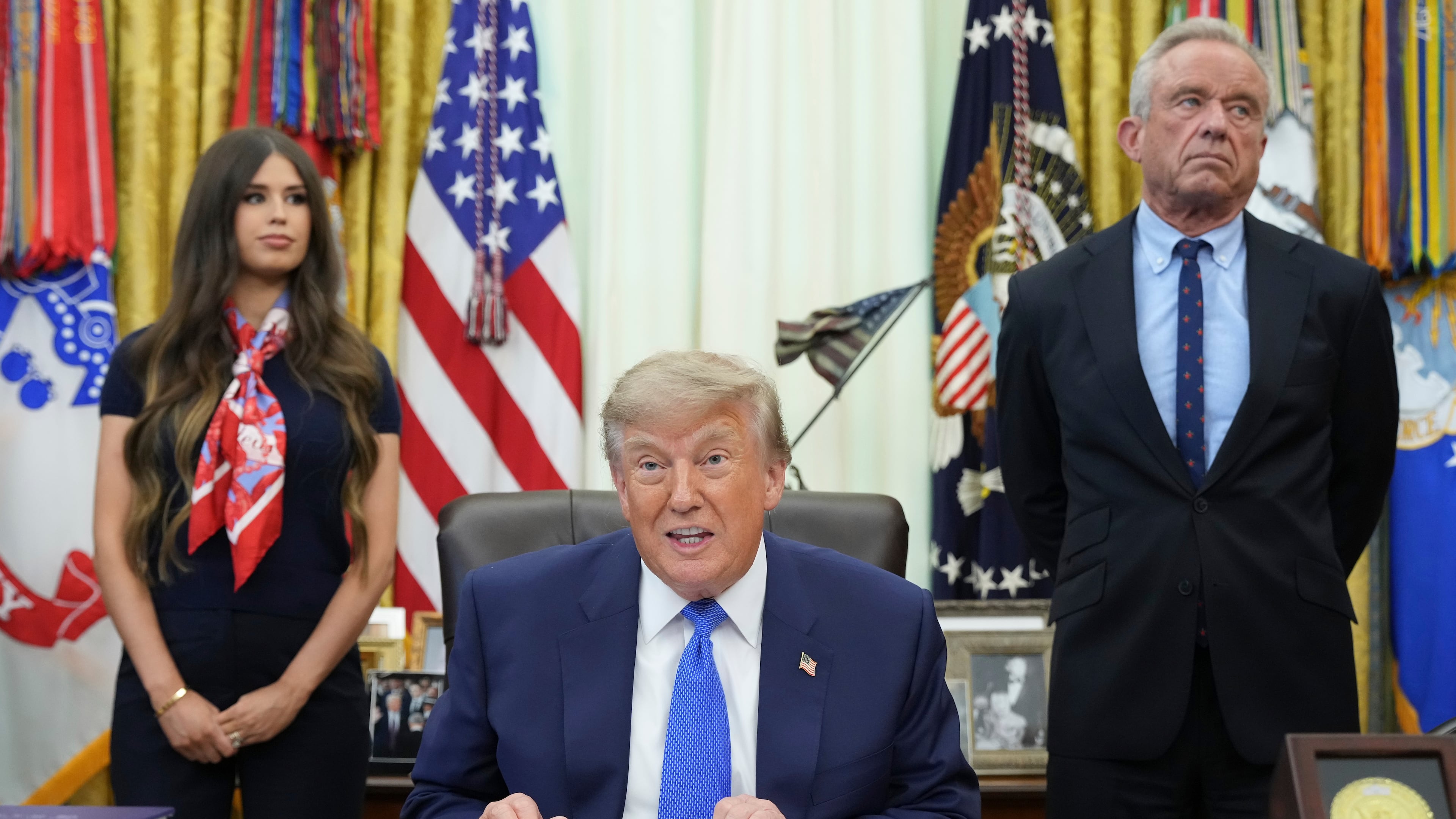 President Donald Trump speaks as Health and Human Services Secretary Robert F. Kennedy Jr., right, and Jayme Franklin listen during a meeting to sign an executive order about vaccines, Monday, Aug. 10, 2026, in the Oval Office of the White House in Washington. (AP Photo/Jacquelyn Martin)