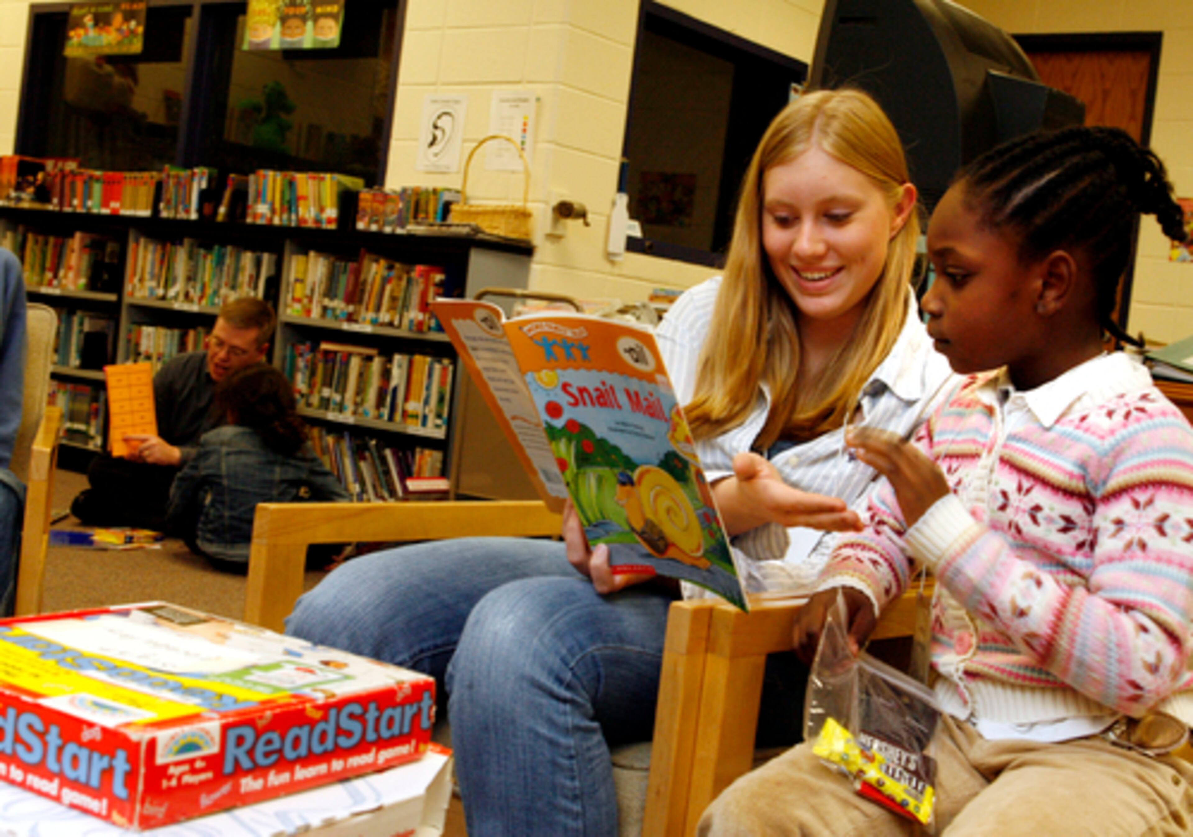 Working together during a free, evening tutorial program at Mimosa Elementary, volunteer Katie Crosby, second from left, gets a five from Andrea Marcellus, right.