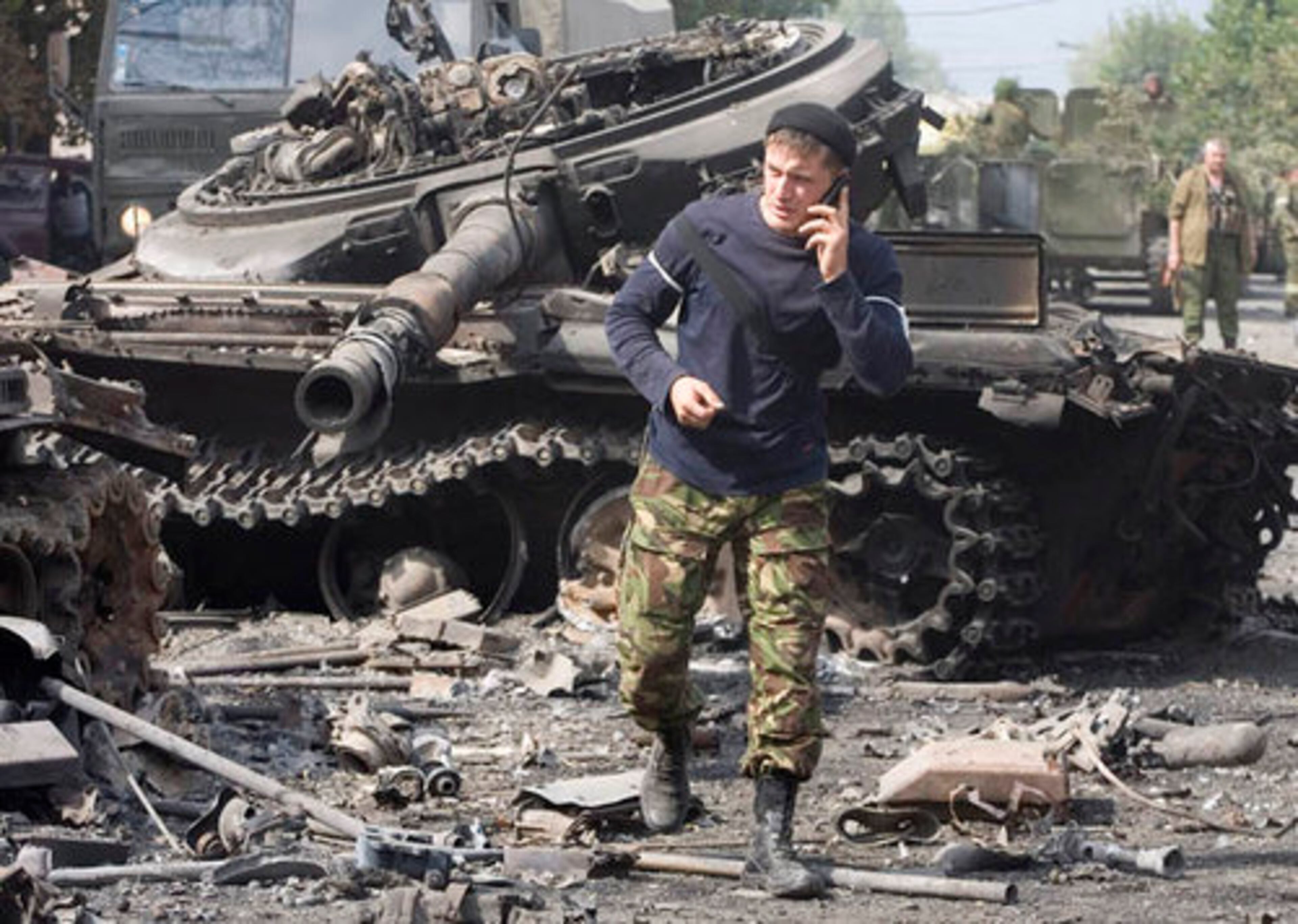 An Ossetian soldier uses a mobile phone as he walks near a destroyed tank in Tskhinvali, capital of Georgian breakaway enclave of South Ossetia.