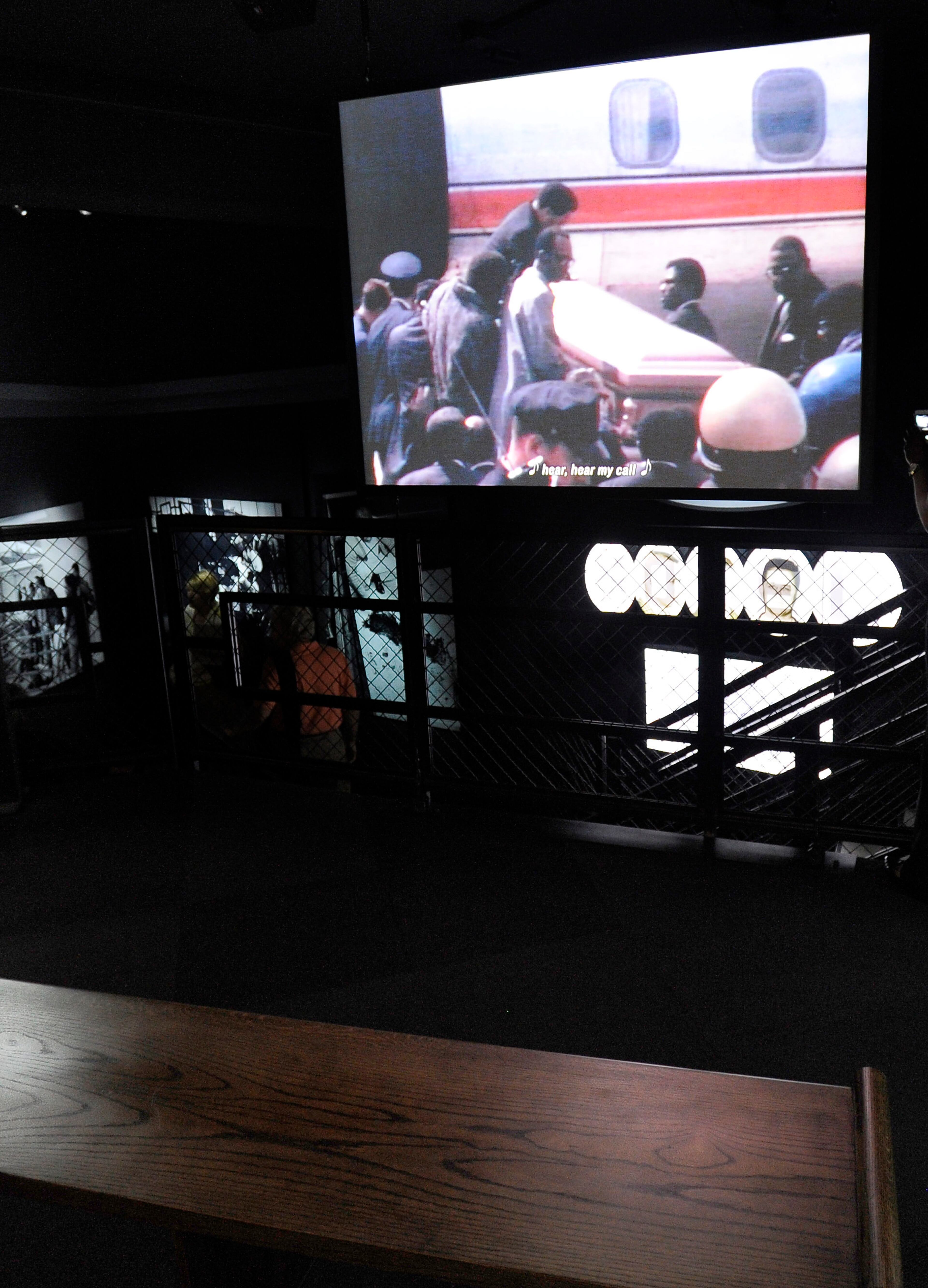From a church pew bench, visitors can view a video showing the plane bearing the coffin of Martin Luther King, Jr., at an exhibit in the National Center for Civil and Human Rights Tuesday, June 10, 2014, in Atlanta. The main exhibits include: the King papers on the first floor, the second floor main entrance, open space and mural, the lunch counter, interactive TV displays, Freedom Rider Bus, and stained glass portraits of four girls killed during violence in Alabama, while the third floor showcases the global human rights footprint with intimate cone-shaped movie theaters and a villains and champions exhibit. David Tulis / AJC Special