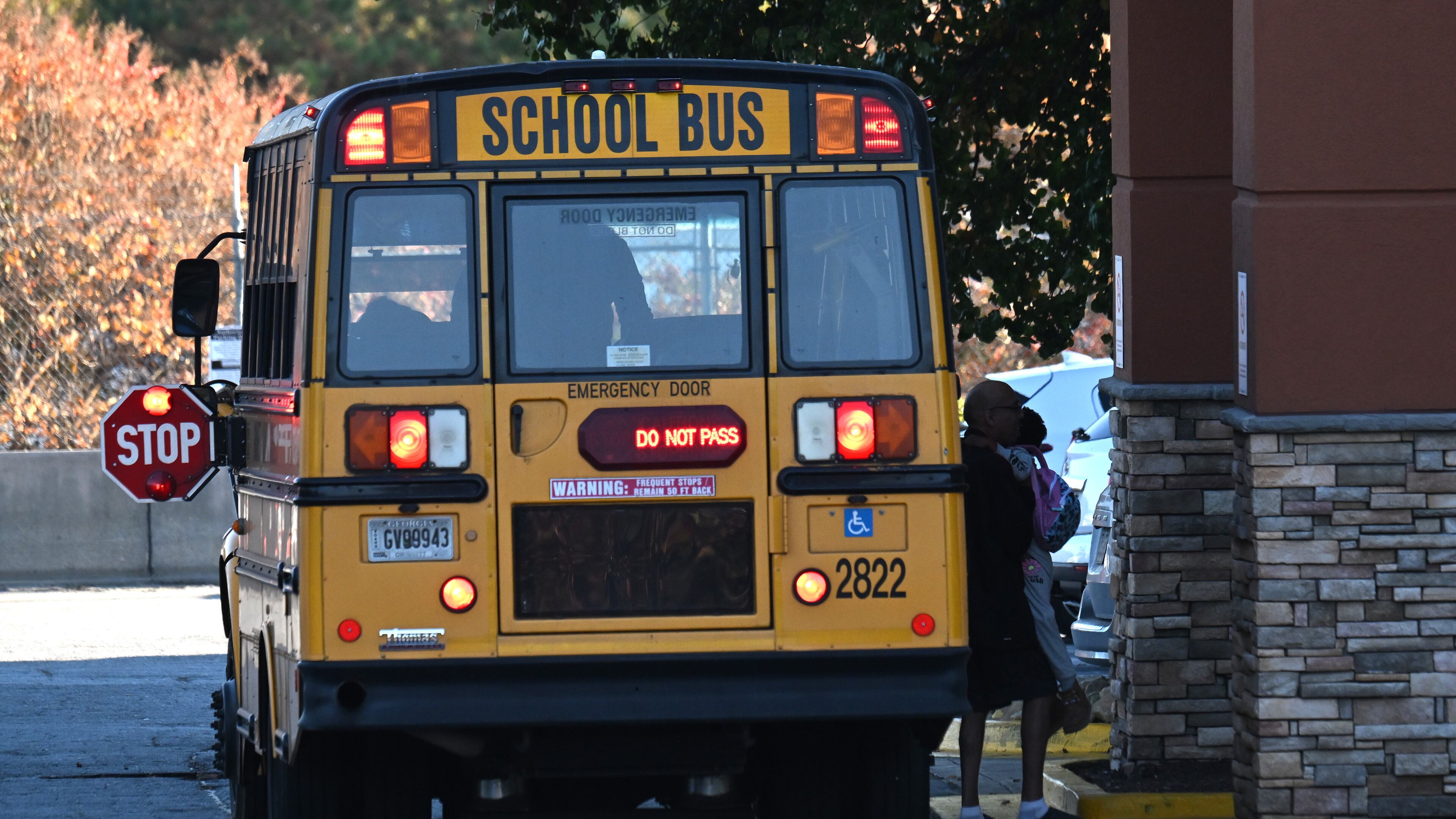 A Gwinnett County school bus drops off a young child at the entry of an extended-stay hotel in Duluth on Tuesday, Nov. 7, 2023. It was one of at least 10 school buses that stopped there that afternoon. Student homelessness is rising. Under federal law, students who live in extended-stay hotels are considered to be homeless, and school districts must transport them to the school they attended before becoming homeless, or to the school they chose after. That means multiple buses from many schools visiting each such hotel. (Hyosub Shin / Hyosub.Shin@ajc.com)