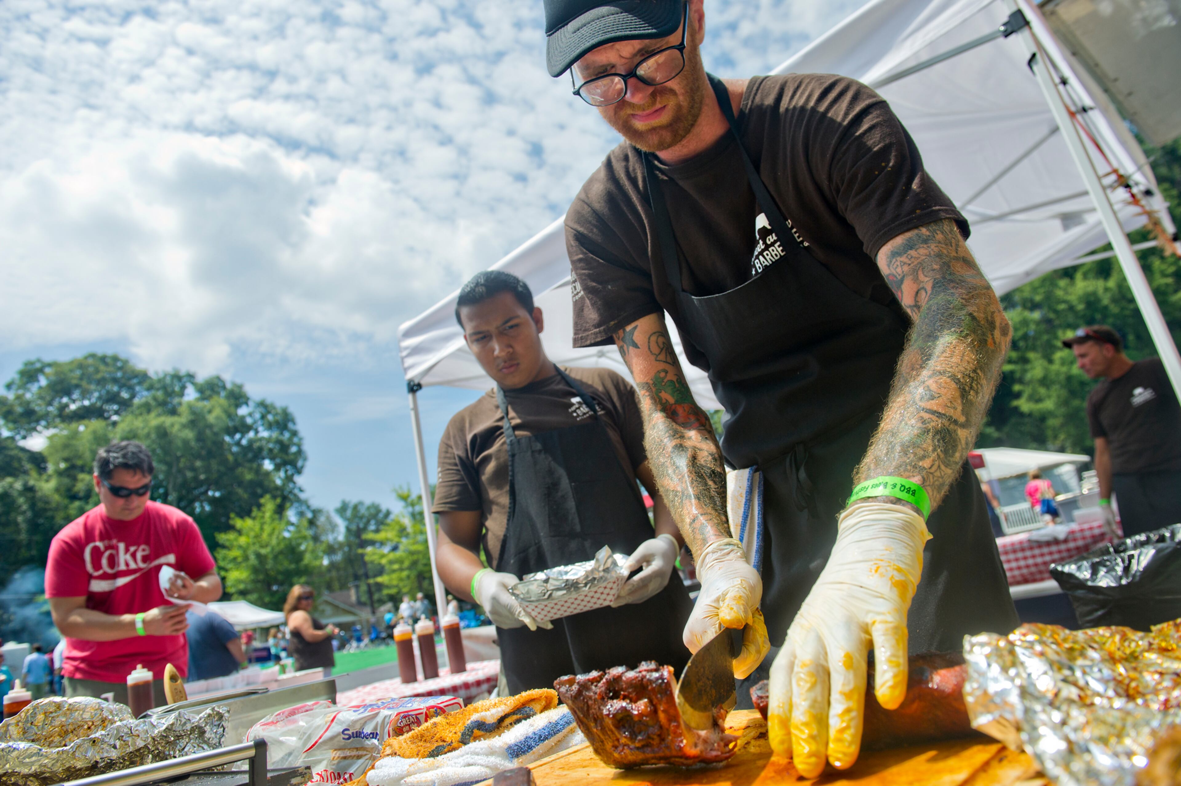 Derek Lord (right) cuts a rack of ribs for Ezequiel Palacios during the Decatur BBQ, Blues & Bluegrass Festival at Harmony Park in Decatur on Saturday, August 16, 2014. The 14th annual festival featured over seven hours of blues and bluegrass performances as well as beer, barbeque and children's activities.