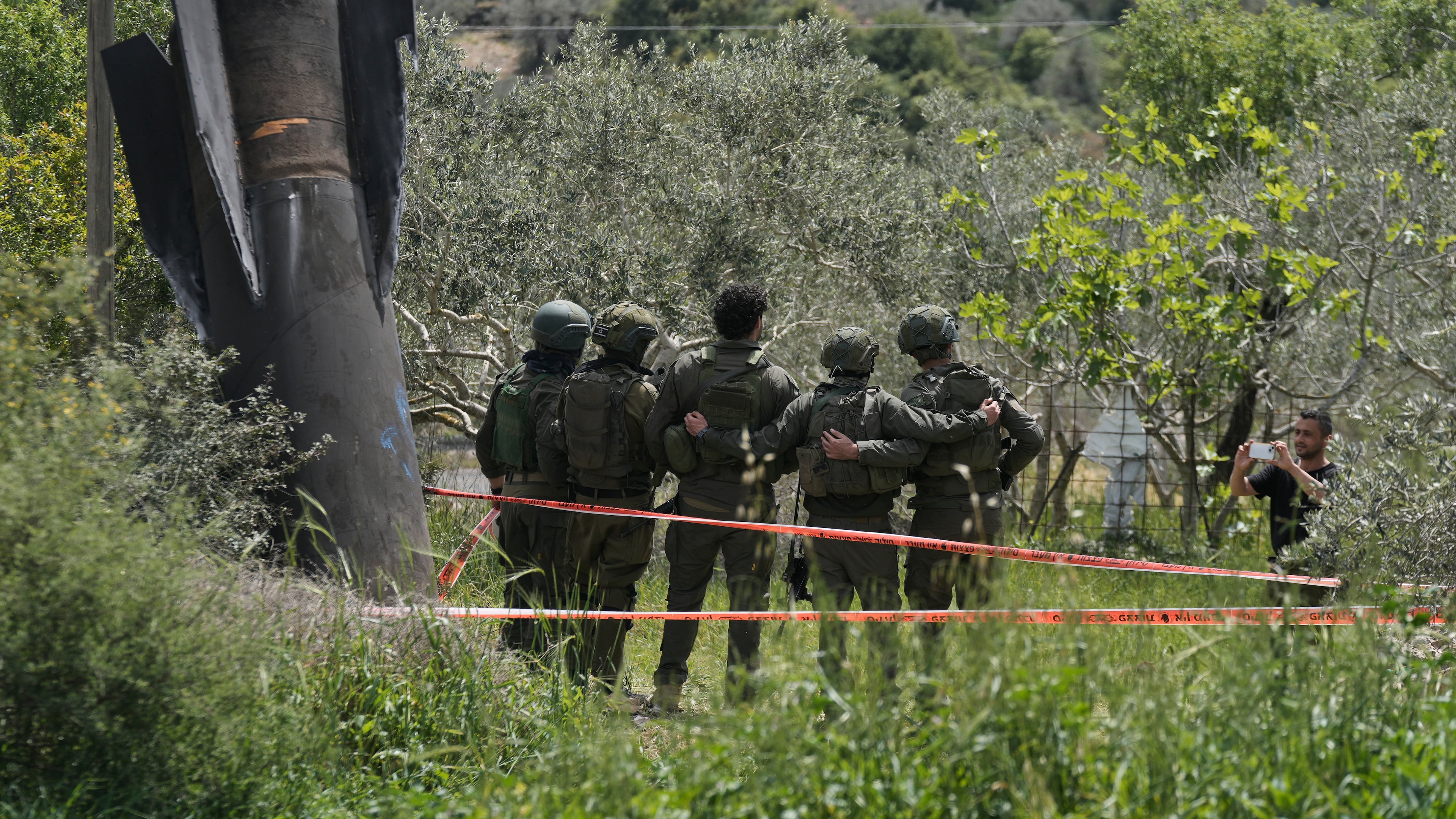 Israeli soldiers take their photo beside the wreckage of an Iranian missile that landed in the West Bank village of Kifl Haris Tuesday, March 24, 2026. (AP Photo/Majdi Mohammed)