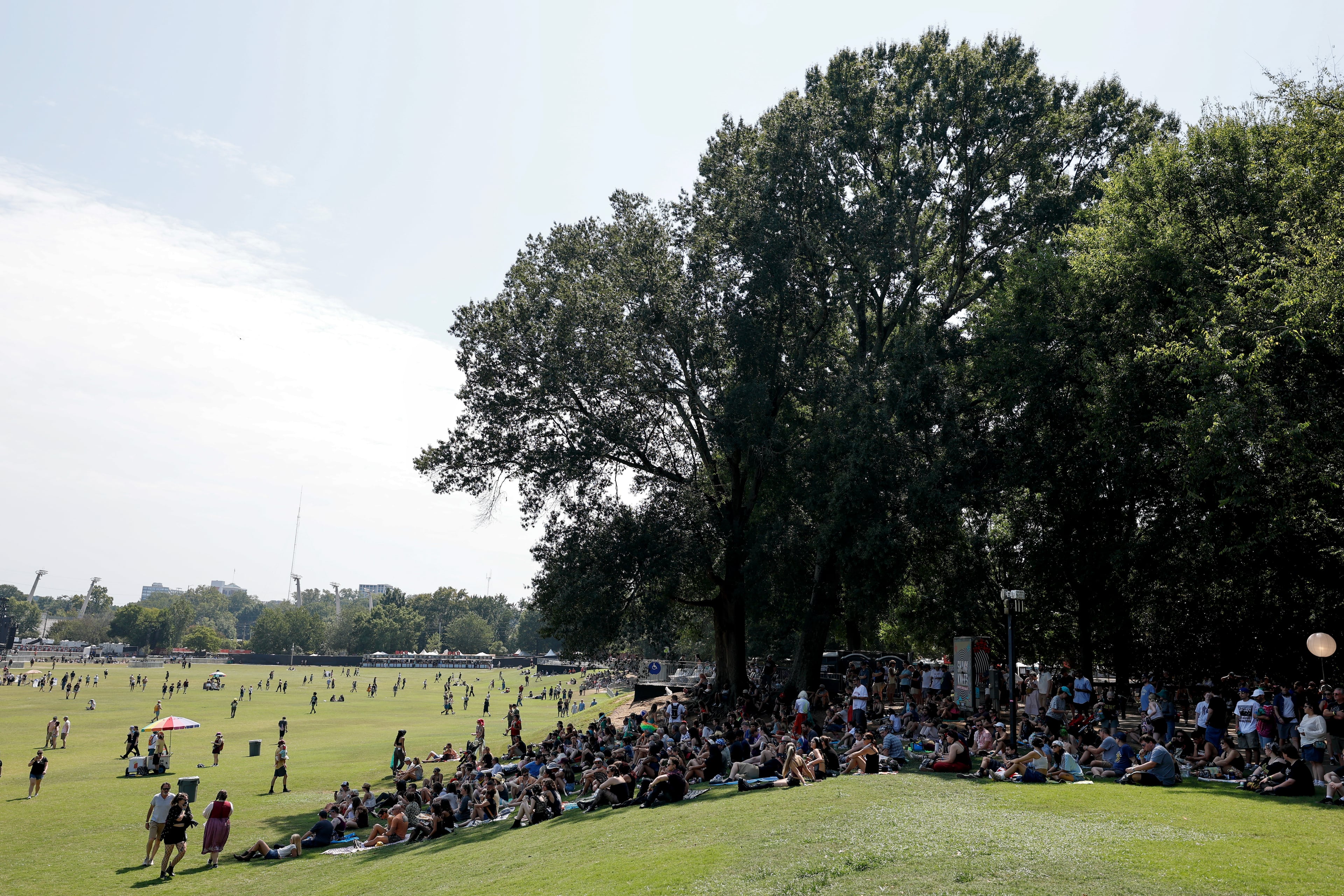 People congregate in the shade under a large tree during the Shaky Knees music festival at Piedmont Park, Saturday, Sept. 19, 2026, in Atlanta. (Erik S. Lesser for the AJC)