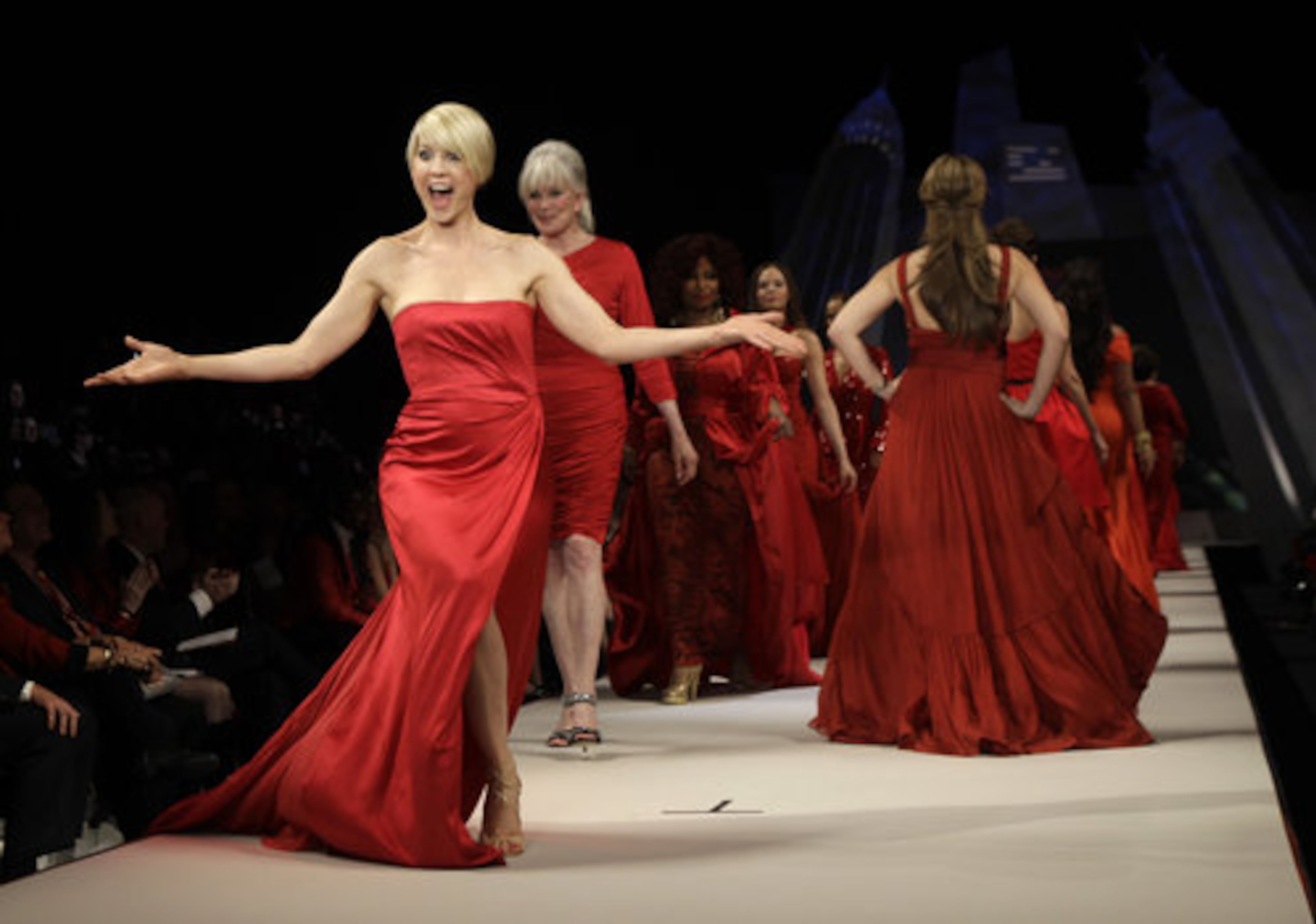 Actress Jenna Elfman, wearing a dress designed by Alberta Ferretti, reacts on the runway with other celebrity models, including Linda Evans, second from right, during the Heart Truth Red Dress fashion show.