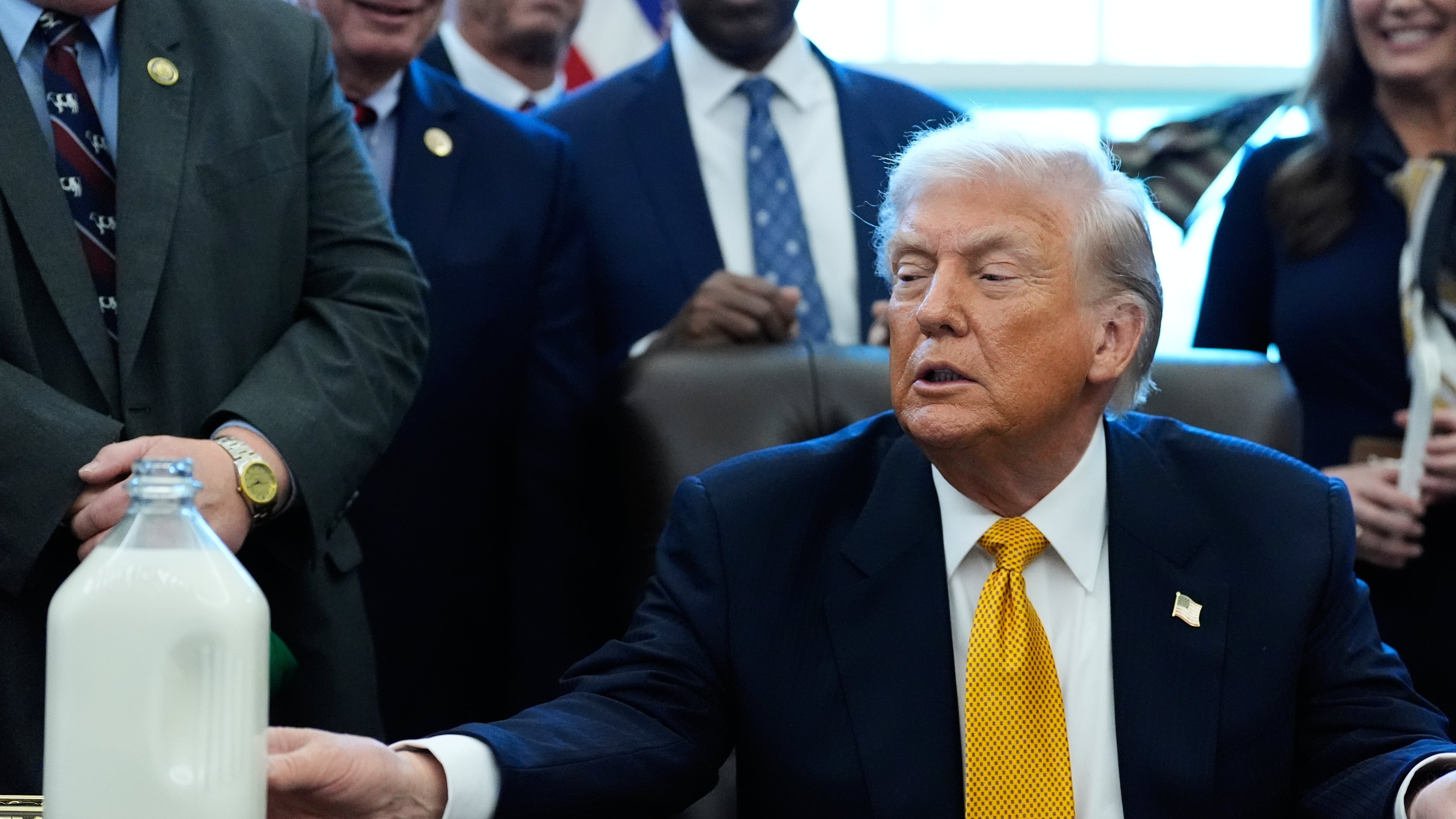 President Donald Trump touches a container of milk as he speaks in the Oval Office of the White House, Wednesday, Jan. 14, 2026, in Washington. (AP Photo/Alex Brandon)