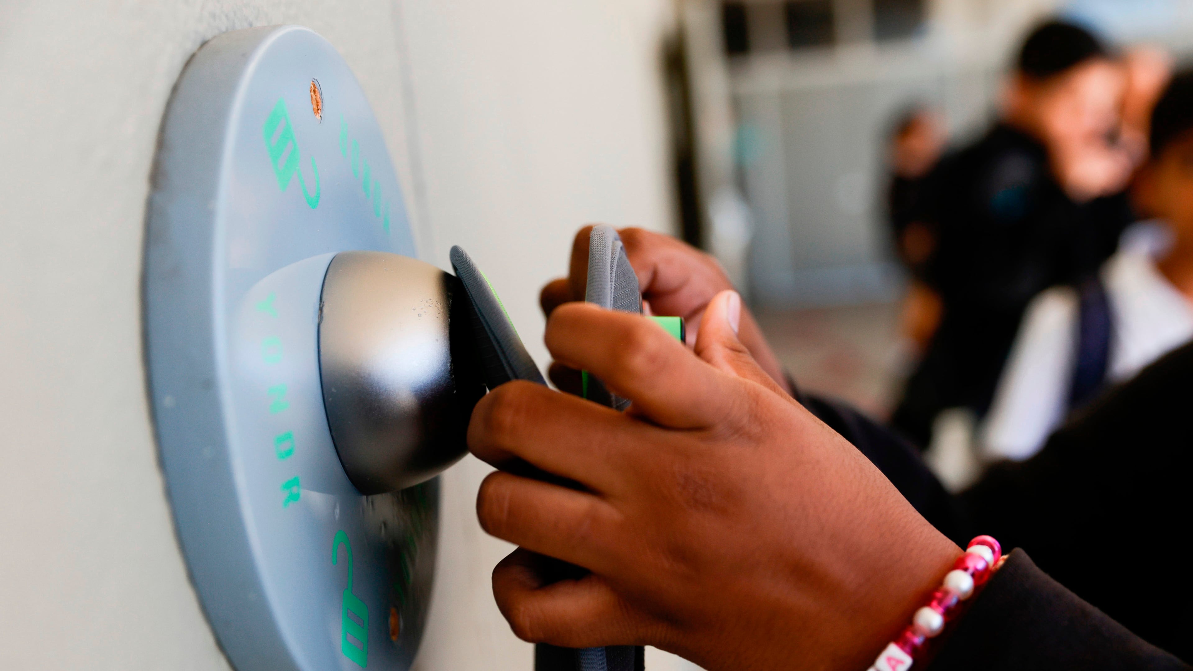 FILE - A middle school student unlocks a Yondr pouch on an unlocking base at Bayside Academy while others wait in line for their turn to unlock their pouch at the end of the school day Aug. 16, 2024, in San Mateo, Calif. (Lea Suzuki/San Francisco Chronicle via AP, File)