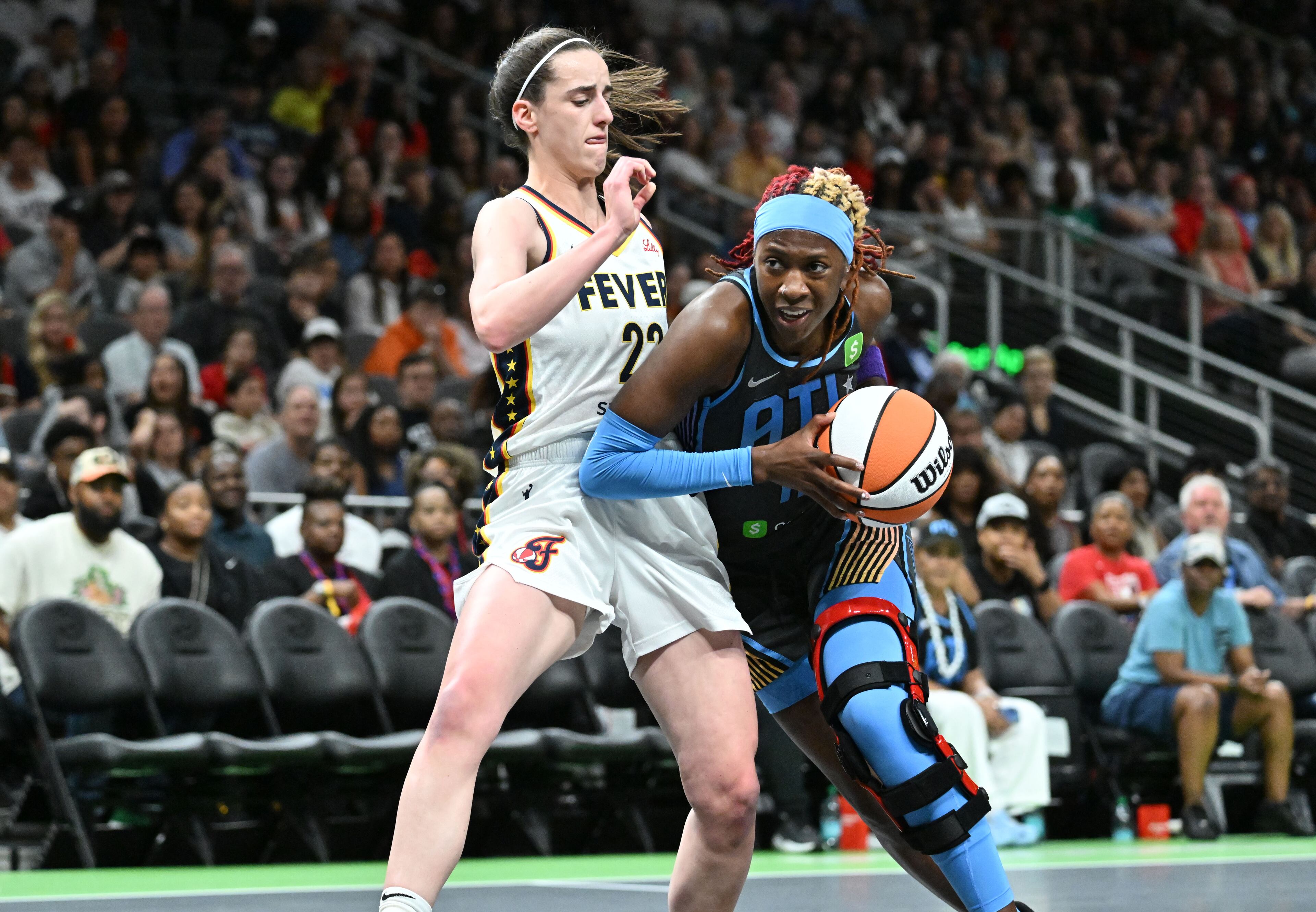 Atlanta Dream guard Rhyne Howard drives against Indiana Fever guard Caitlin Clark during Thursday's game. Beyond her stat line, Howard’s energy fueled her team, from the dustup with Clark at center court to her defensive efforts. (Hyosub Shin/AJC)