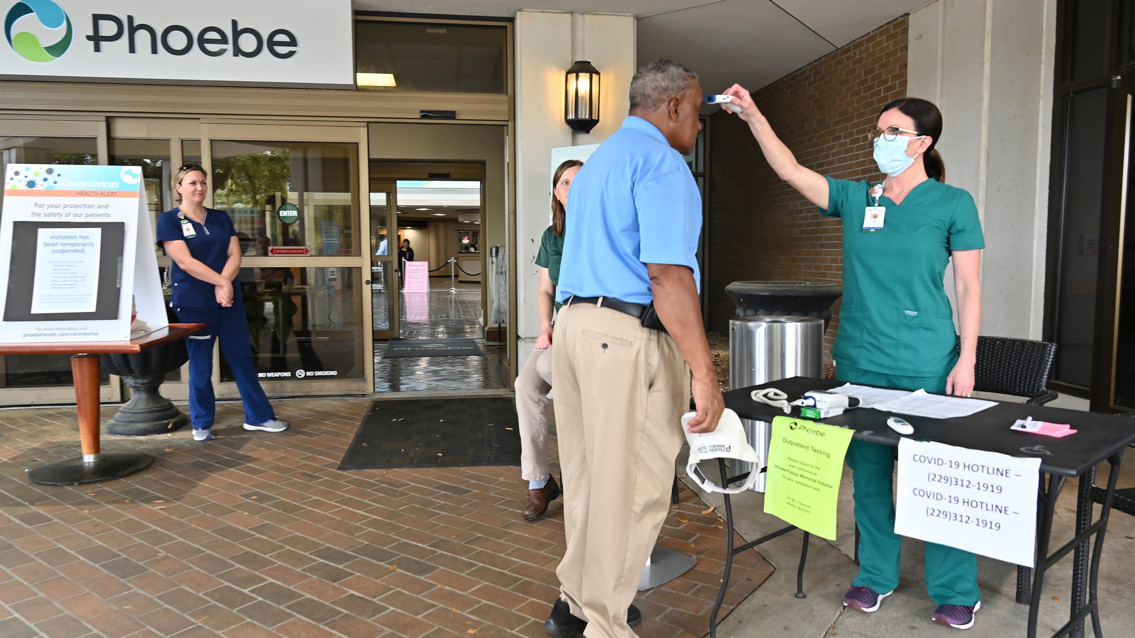 A nurse checks a temperature of an employee before he enters the Phoebe Putney Memorial Hospital in Albany on Tuesday, March 24, 2020. Well off the interstate some 180 miles south-southwest of Atlanta, Albany's struggles with the coronavirus stick out like a sore thumb on the state's map. (Hyosub Shin / Hyosub.Shin@ajc.com)