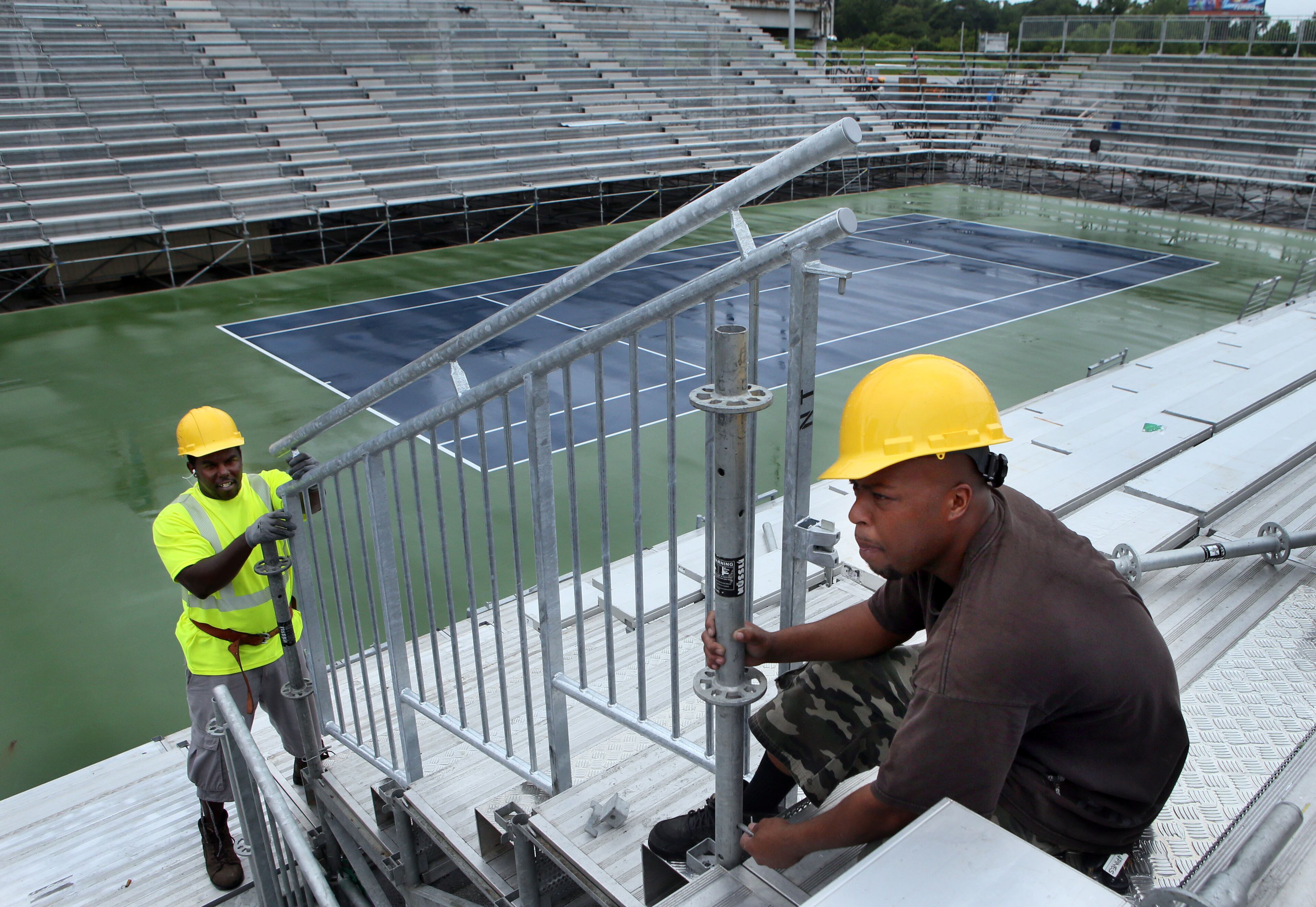 DeAndre Brooks (left) and Joedanta Collins install hand rails as crews construct the grand stands for the upcoming BB&T Atlanta Open men's pro tennis event at Atlantic Station.