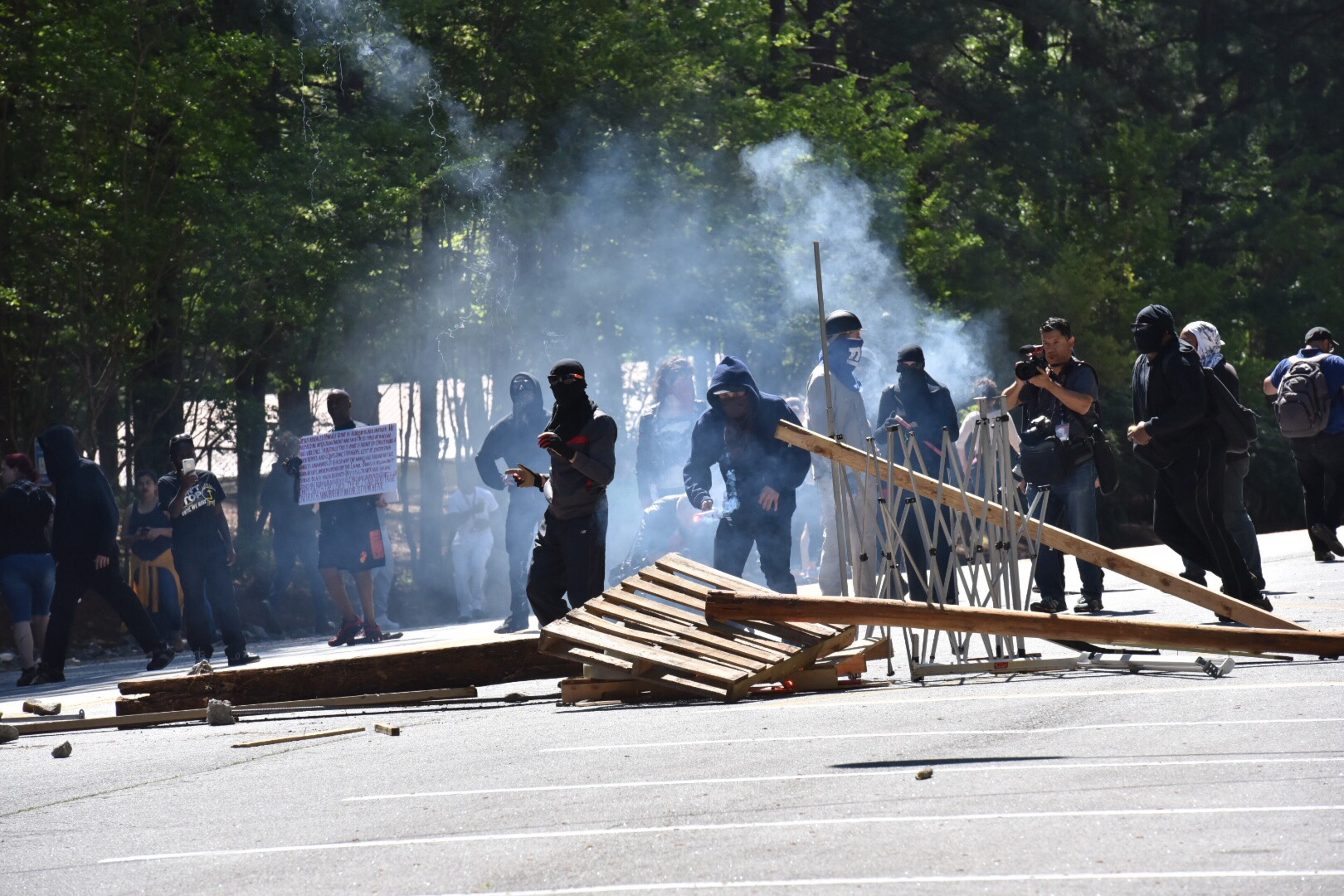 Counter-protesters opposing a "white power" rally throw rocks and chairs at state troopers at Stone Mountain on Saturday, April 23, 2016 in Ga. Later, they set the barricade on fire.