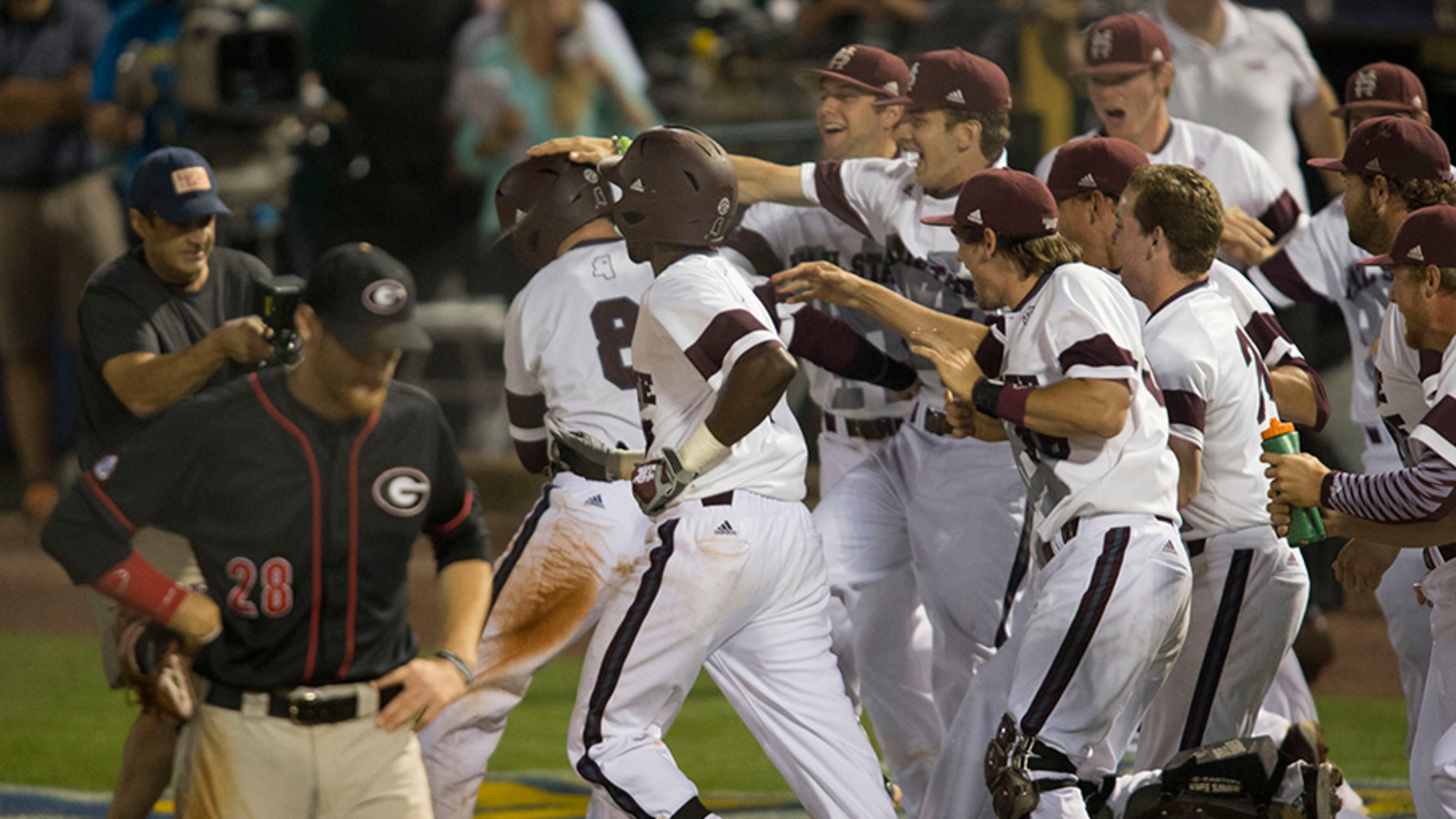Georgia's Heath Holder walks off the field as Mississippi State players storm the field to celebrate their 10-inning 5-4 win in the Southeastern Conference NCAA college baseball tournament Tuesday, May 20, 2014, in Hoover, Ala.
