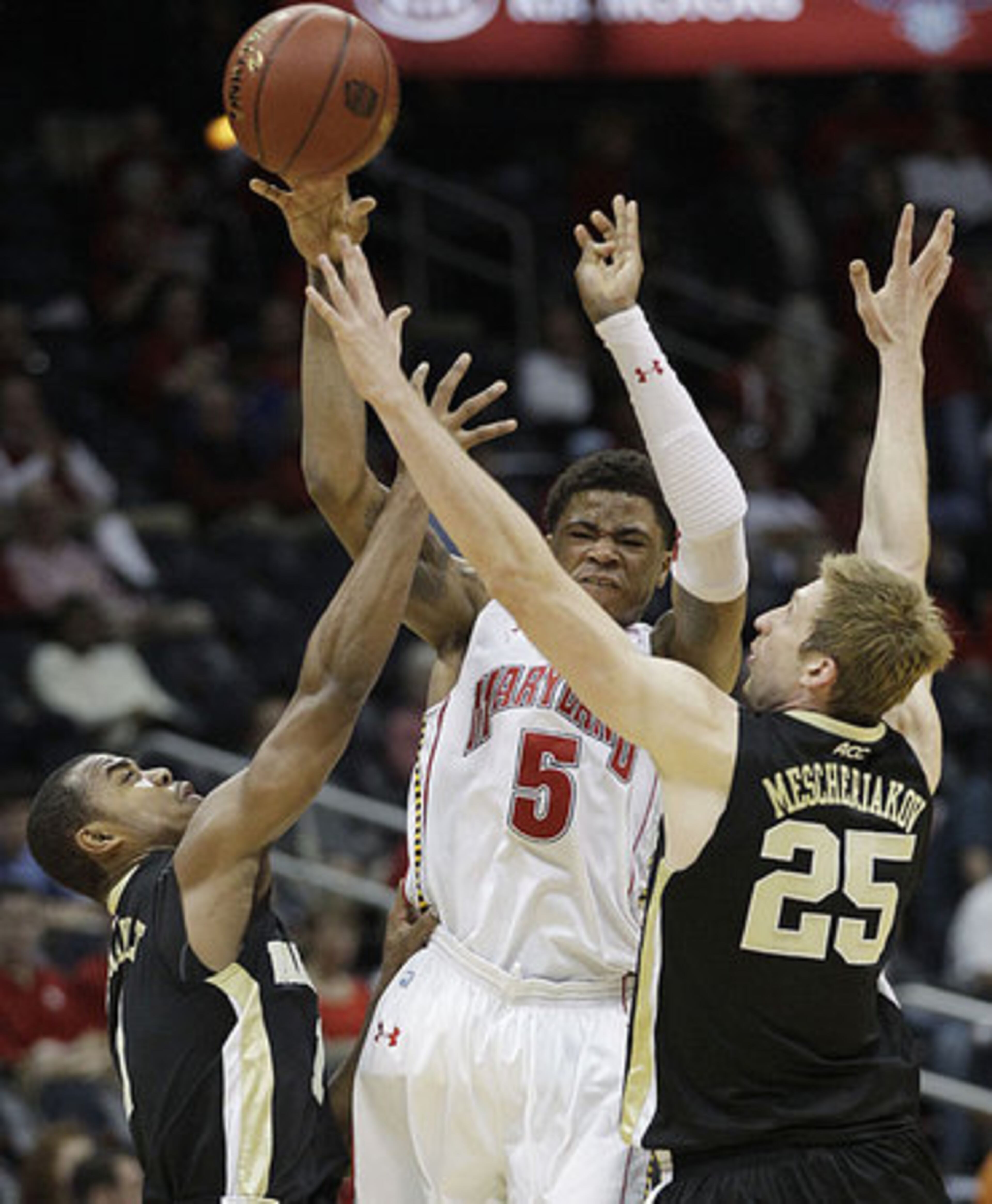 Maryland guard Nick Faust (5) passes the ball under pressure from Wake Forest guard Tony Chennault, left, and Wake Forest forward Nikita Mescheriakov (25) in the second half of an NCAA college basketball first round game at the Atlantic Coast Conference tournament.