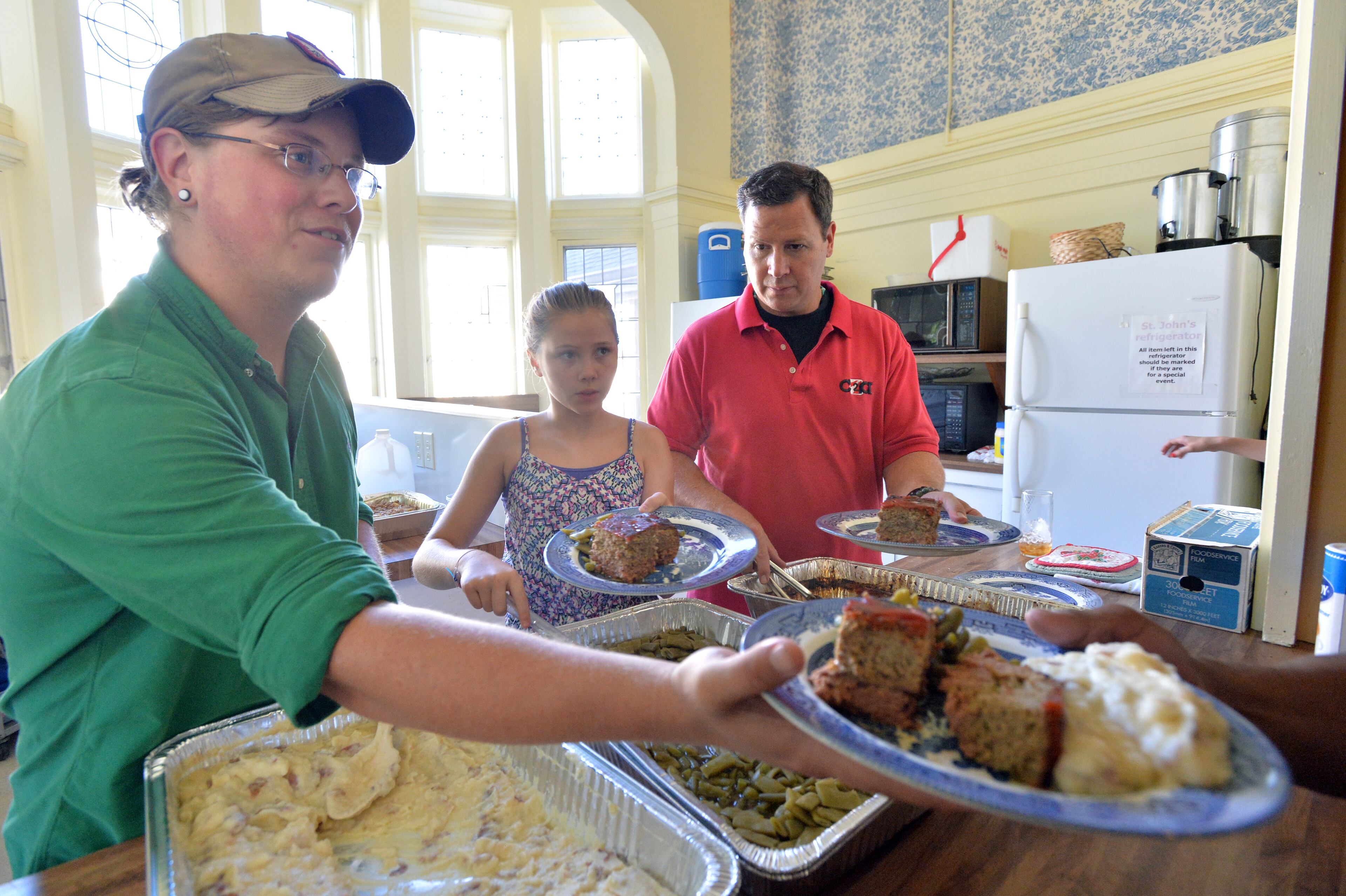 Jeremy Turner (right), executive director of Contribute2America, serves with his daughter Jamie, 10, and Joseph Doyle-Davison (left) during a church dinner for the homeless at St. John's Lutheran Church in Atlanta. HYOSUB SHIN / HSHIN@AJC.COM