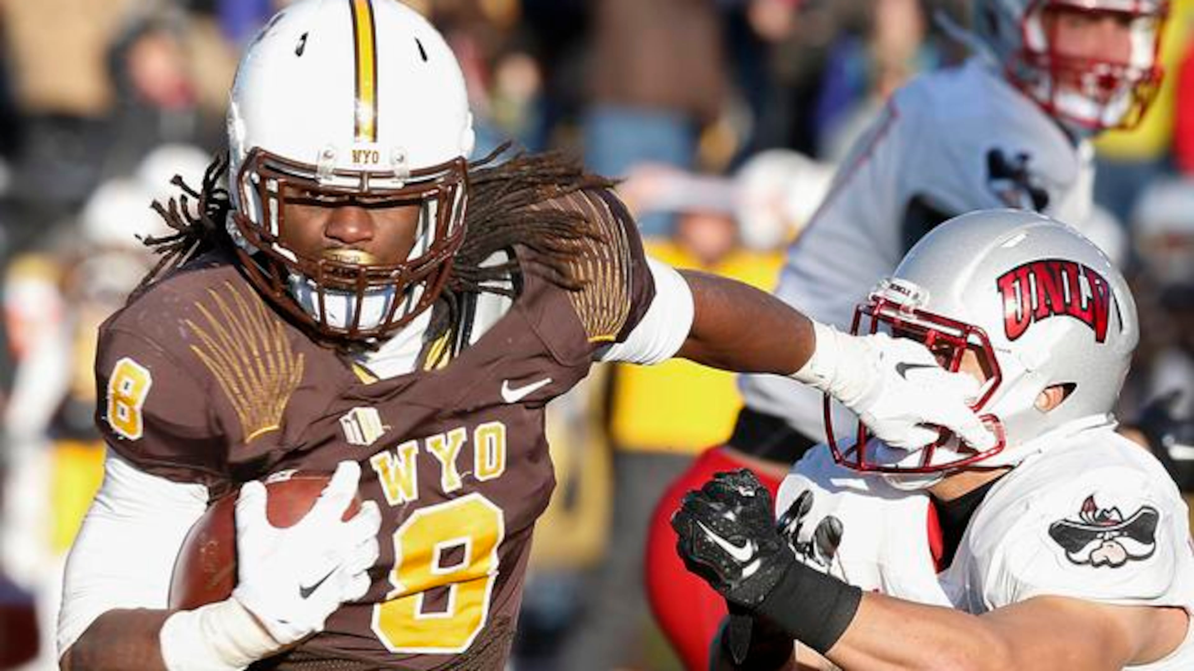 Wyoming running back Brian Hill stiff arms UNLV linebacker Matt Lea during the fourth quarter of an NCAA college football game, Saturday, Nov. 28, 2015, in Laramie, Wyo. (AP Photo/Michael Smith)
