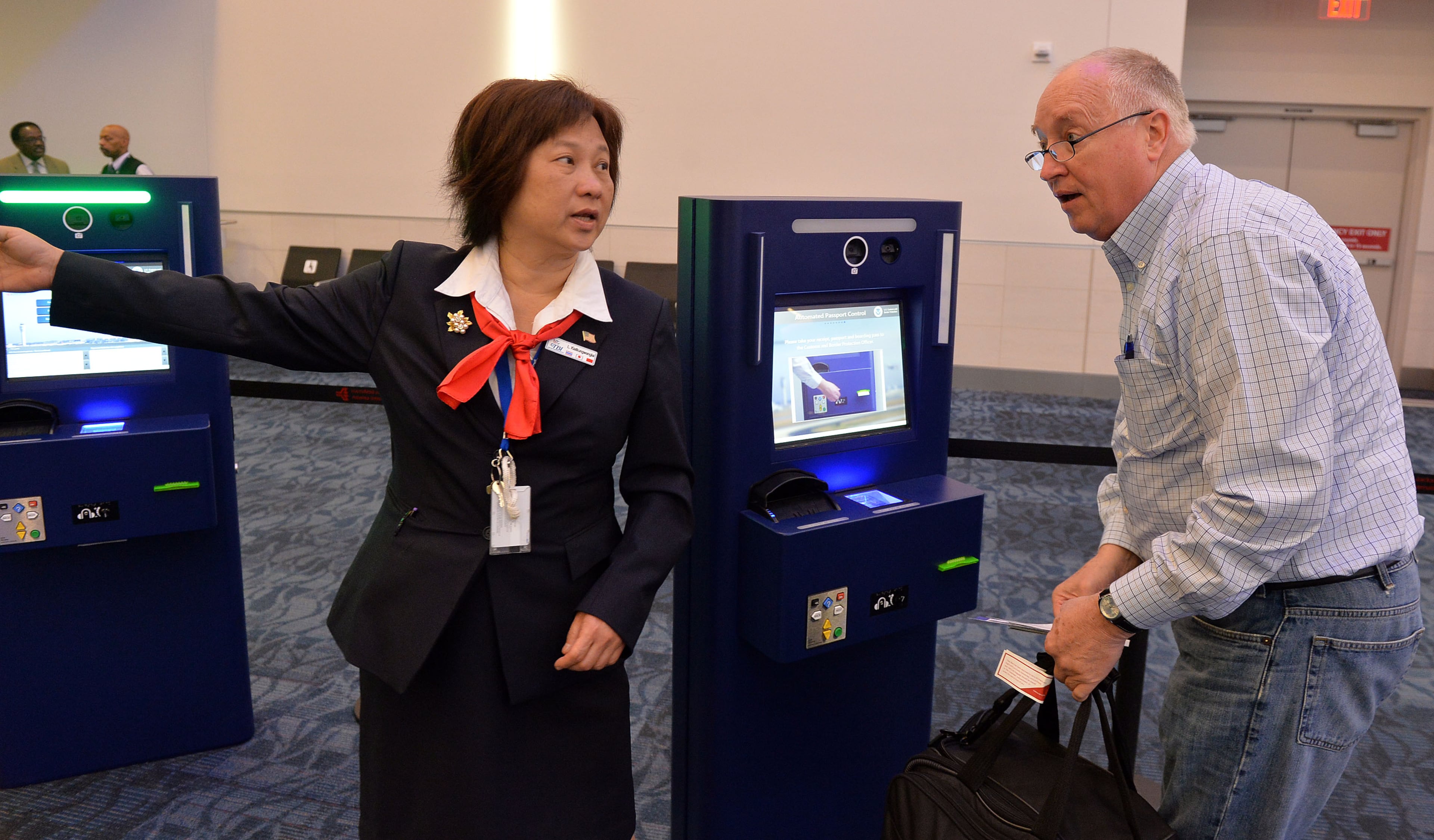 Interpreter Laead Kiatkungwanglai assists traveler Paul Terry of Salt Lake City during the operation of the kiosks Thursday. KENT D. JOHNSON/KDJOHNSON@AJC.COM
