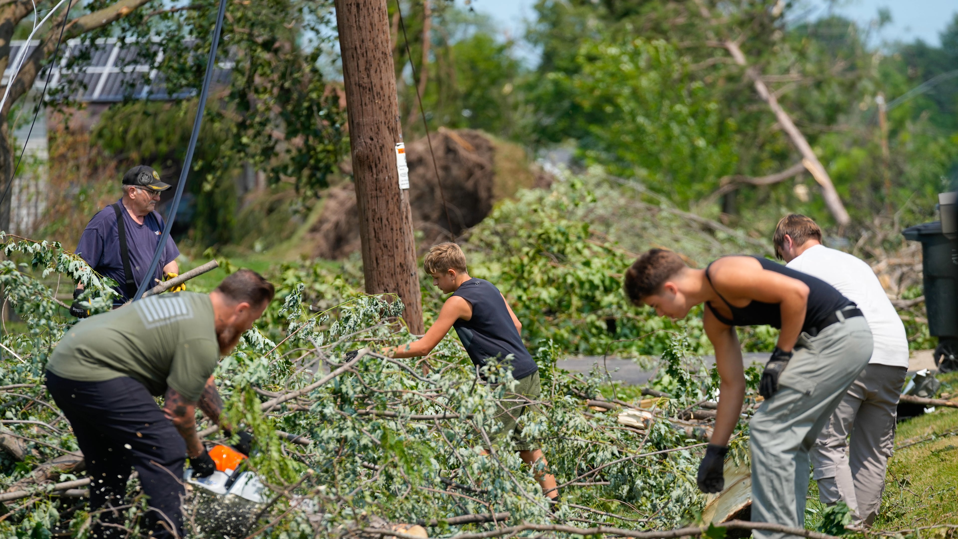 Volunteers help clear tree limbs near a damaged house after a tornado hit the day before in Appleton, Wis., Tuesday, July 28, 2026. (AP Photo/Kayla Wolf)