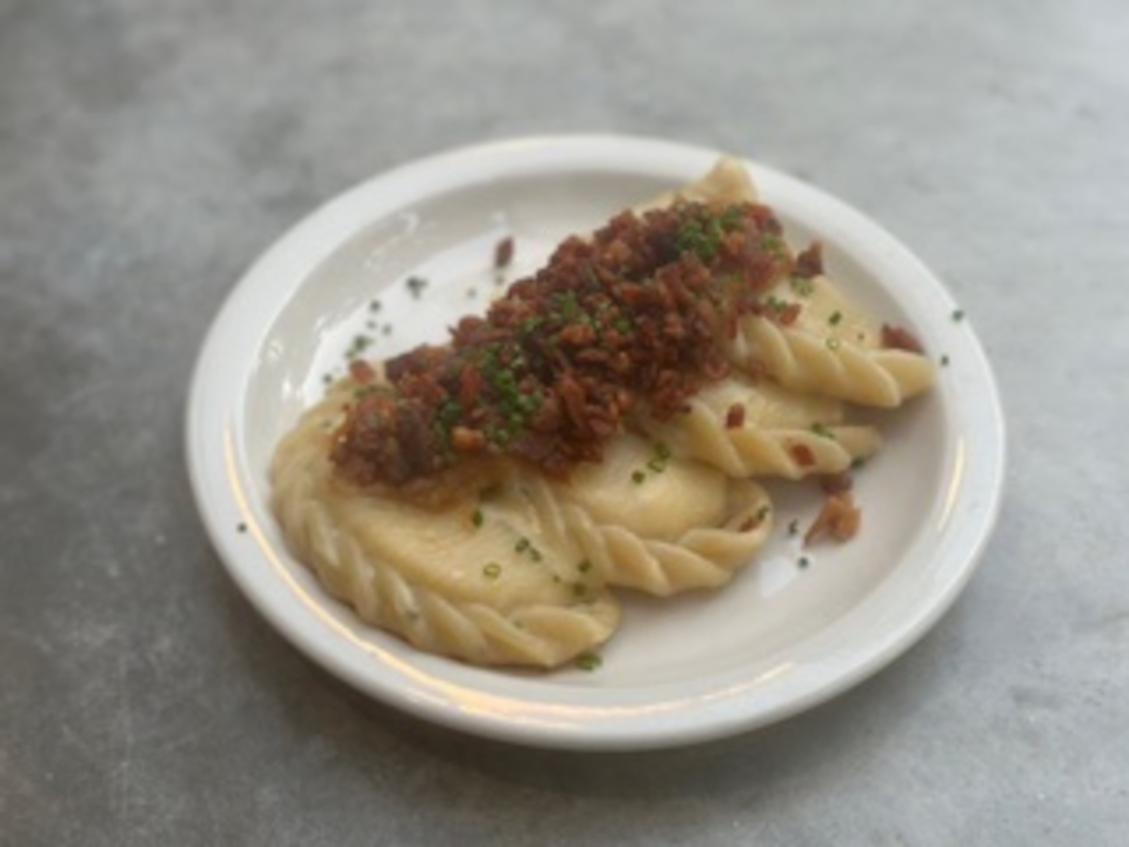 Plated house pierogi topped with bacon. (Courtesy of Basia Piechoczek)