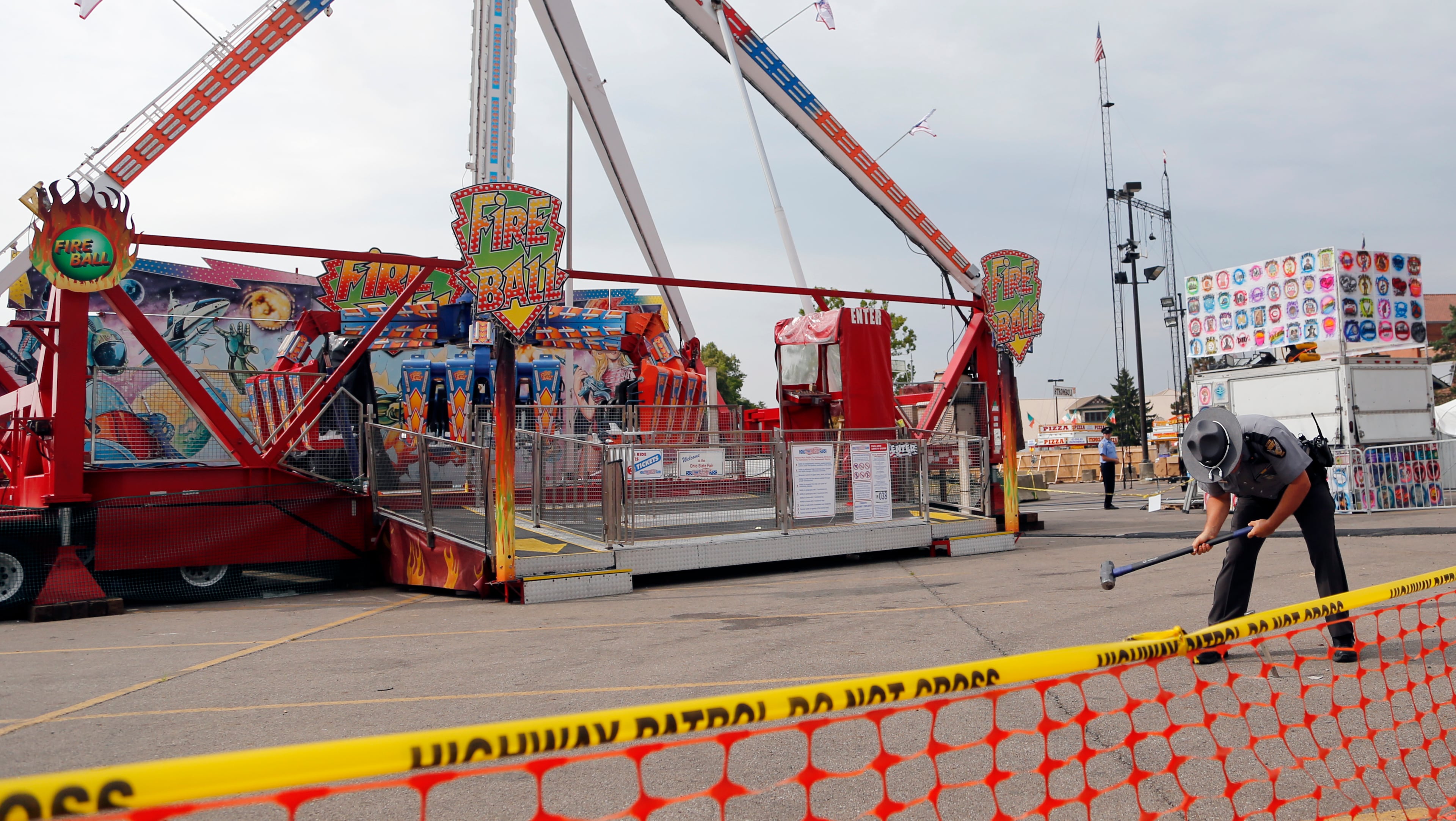 An Ohio State Highway Patrol trooper removes a ground spike from in front of the fire ball ride at the Ohio State Fair Thursday, July 27, 2017, in Columbus, Ohio. The fair opened Thursday but its amusement rides remained closed one day after Tyler Jarrell, 18, was killed and seven other people were injured when the thrill ride broke apart and flung people into the air. (AP Photo/Jay LaPrete)