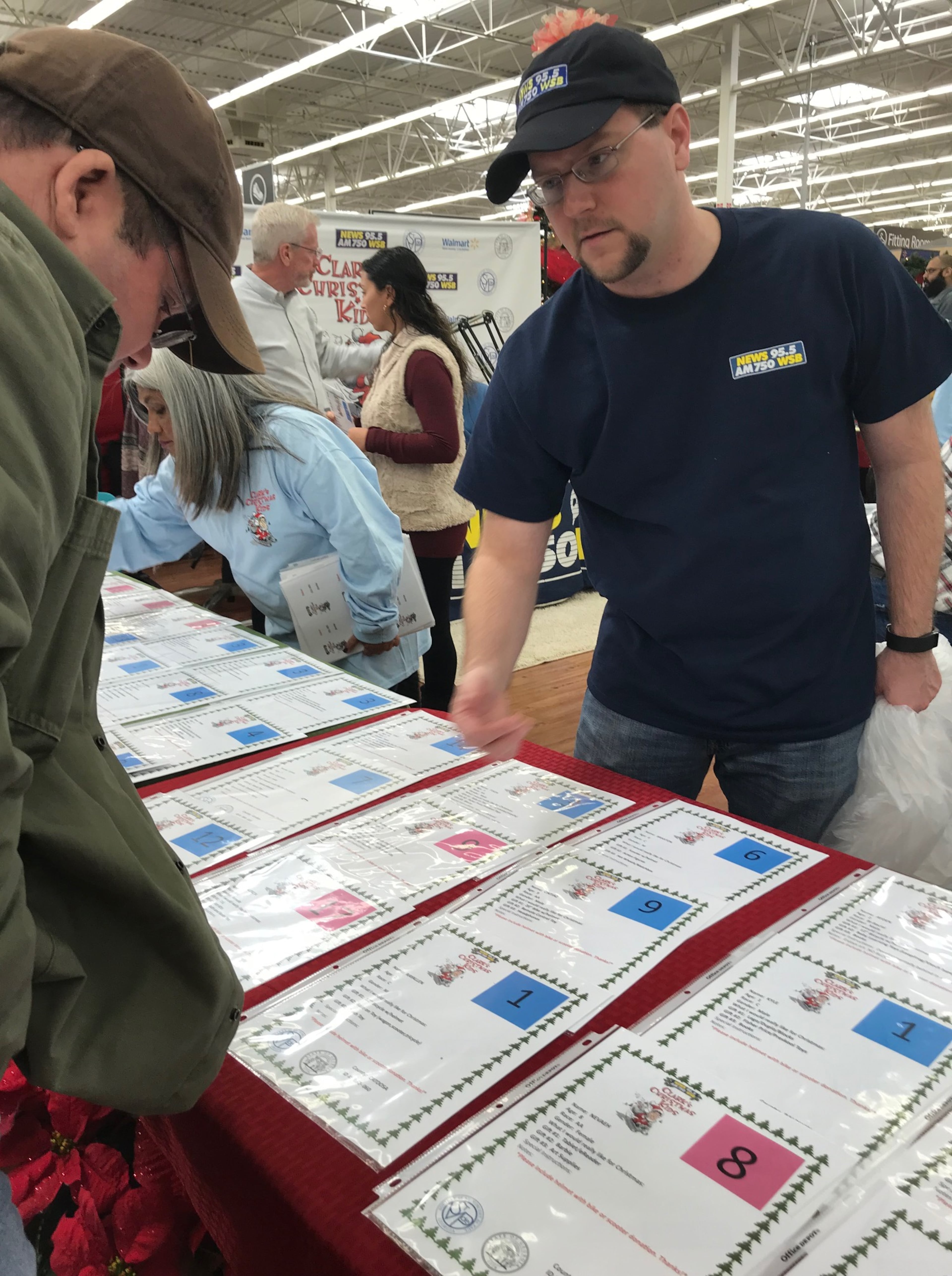 Justin Tysinger, promotions at WSB, informs a customer about how Clark Christmas Kids work. CREDIT: Rodney Ho/rho@ajc.com