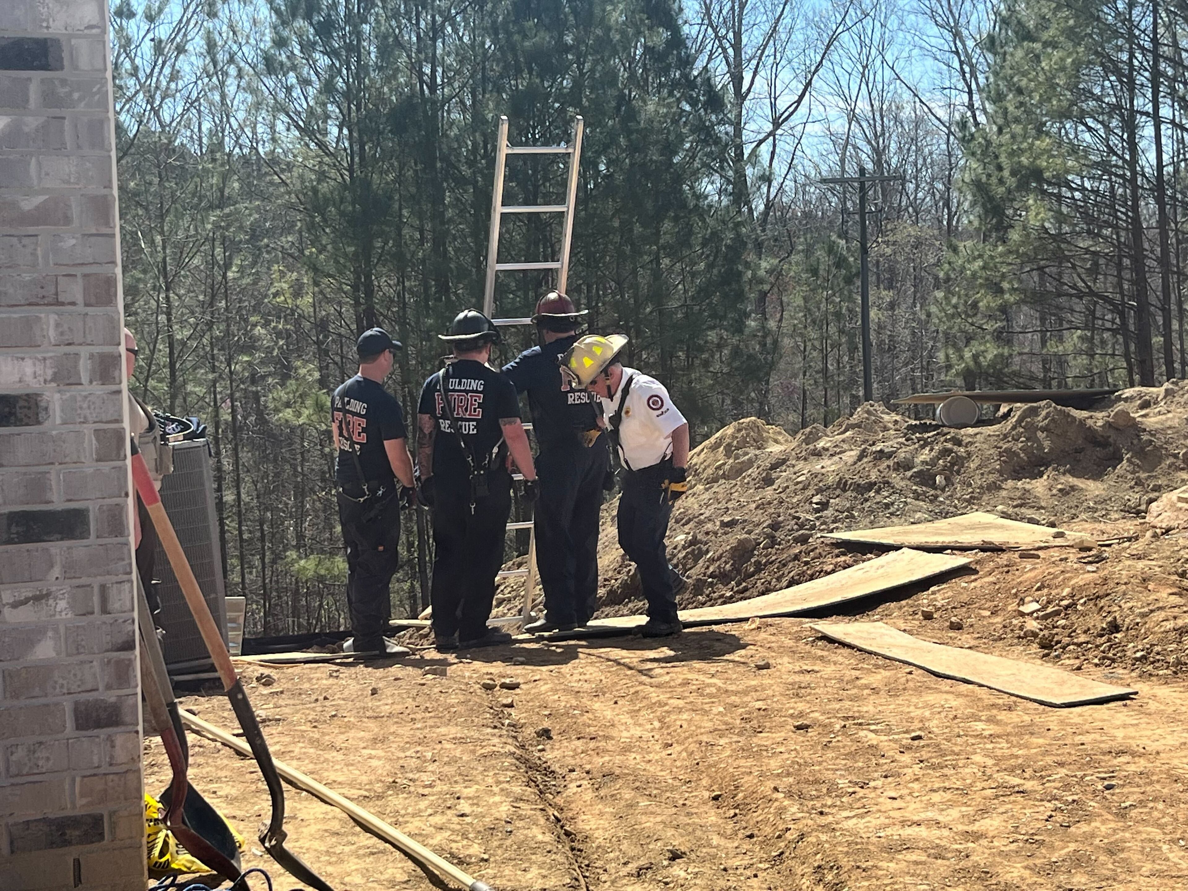 Firefighters examine the trench after the construction worker was pulled free.