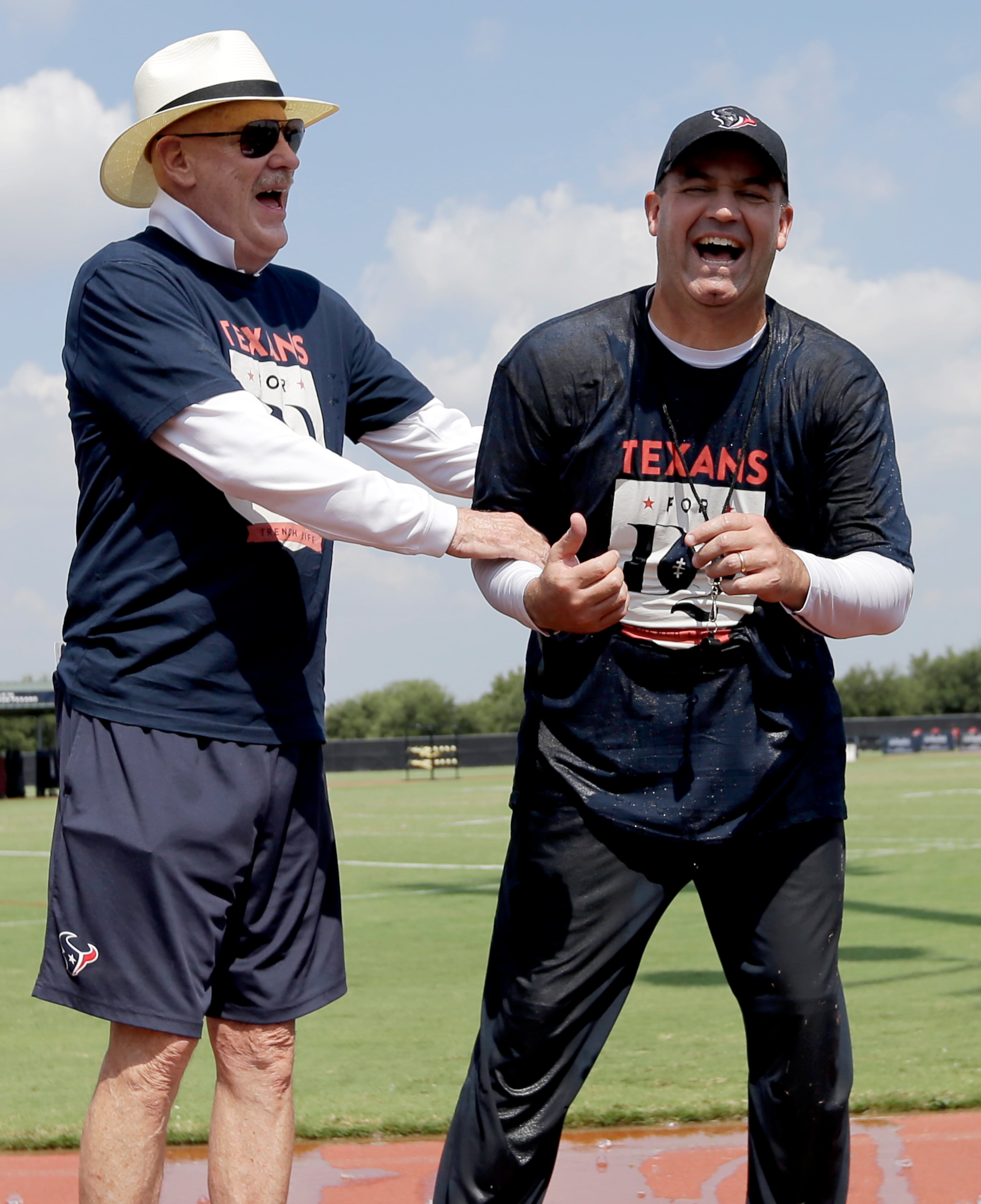Houston Texans owner Bob McNair, left, jokes with coach Bill O'Brien, right, after O'Brien dumped a bucket of ice cold water over his head after an NFL football training camp practice Thursday, Aug. 14, 2014, in Houston. O'Brien was challenged to take the ALS Ice Bucket Challenge to raise money for the ALS Association. The challenge, a social media phenomenon, is part of a program launched by the ALS Association to raise money for fighting ALS, also known as Lou Gehrig's disease. Participants challenge others on video to do it or donate money to ALS before dumping ice cold water over their heads. (AP Photo/David J. Phillip)