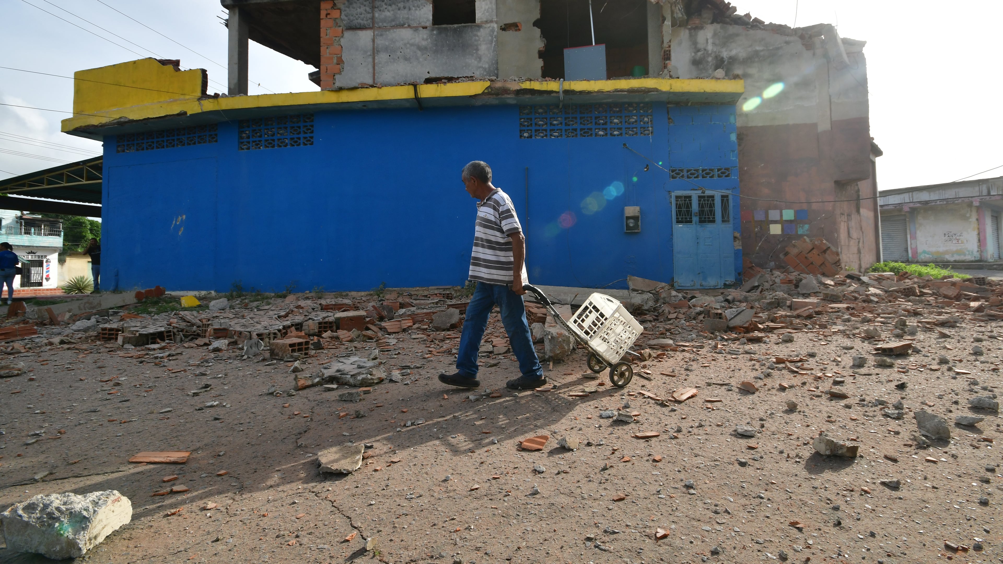 A man walks past a damaged home in Moron, near the epicenter of two earthquakes that struck Venezuela the day before, Thursday, June 25, 2026. (AP Photo/Jacinto Oliveros)