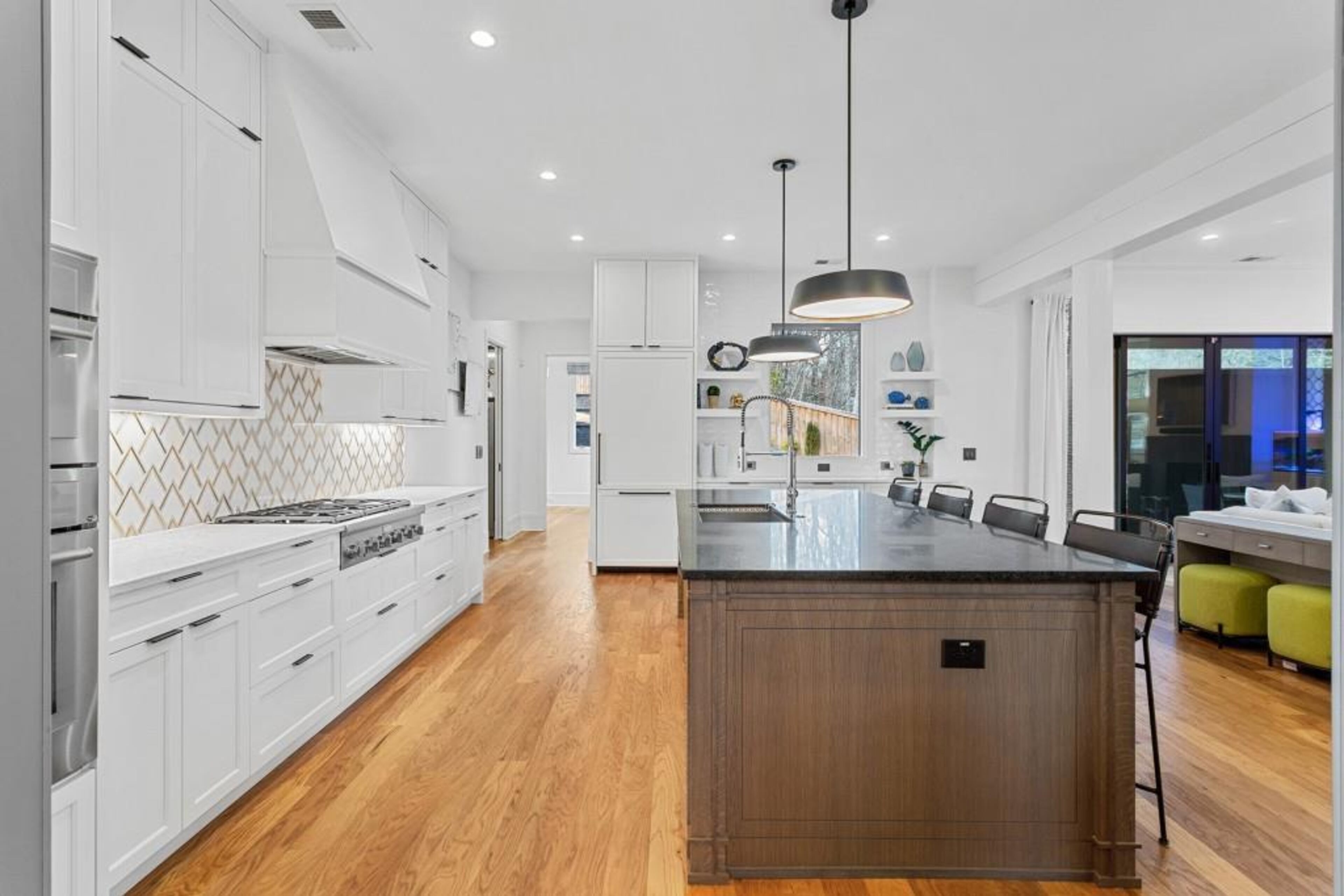 Chef's kitchen featuring oversized island with honed quartzite countertops, commercial grade stainless steel appliance package, custom backsplash, walk-in pantry and an abundance of storage space.