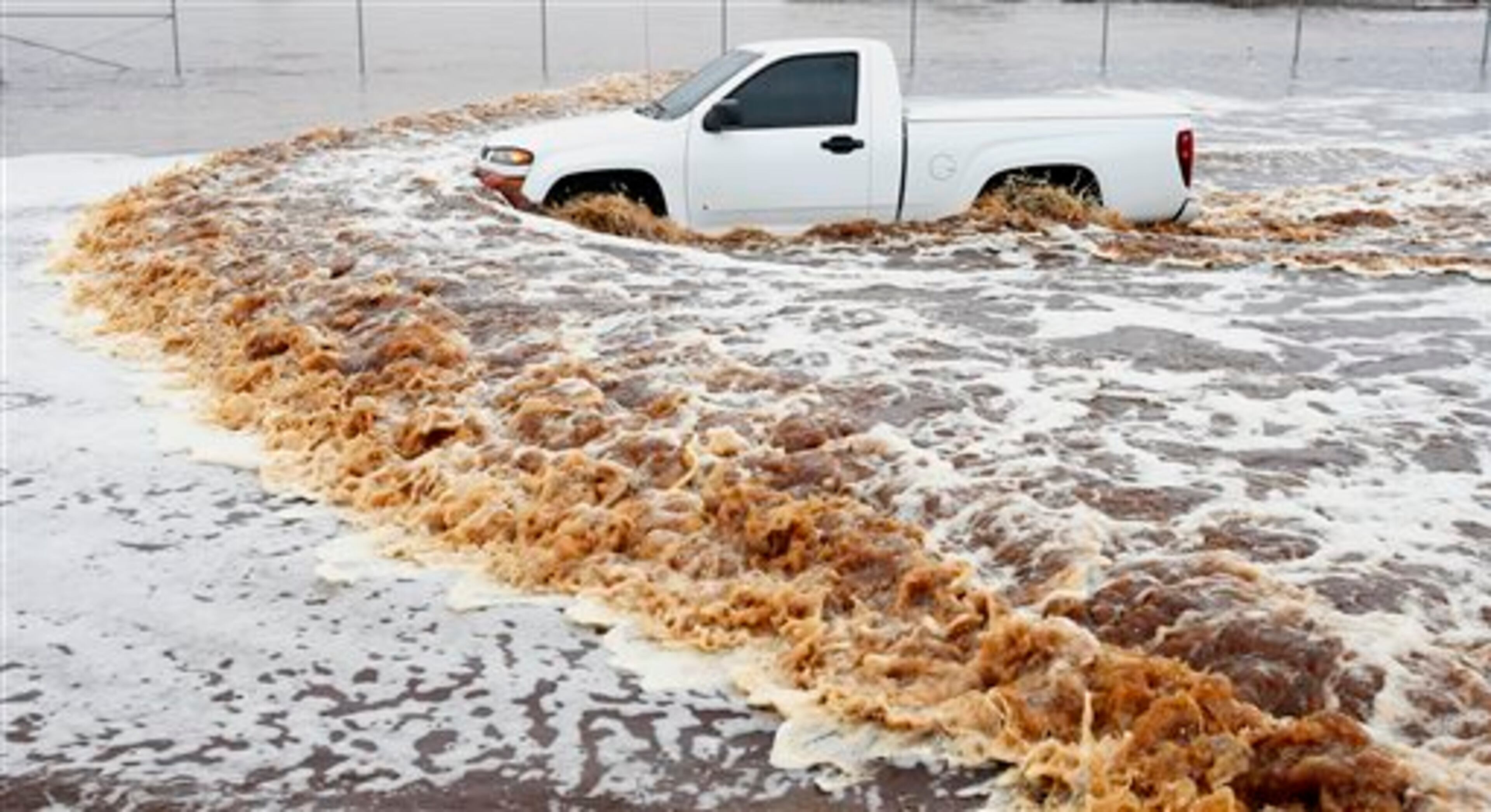 A truck creates a wake as its driver tries to navigate a severely flooded street as heavy rains pour down Monday, Sept. 8, 2014, in Phoenix. Storms that flooded several Phoenix-area freeways and numerous local streets during the Monday morning commute set an all-time record for rainfall in Phoenix in a single day. (AP Photo/Ross D. Franklin)