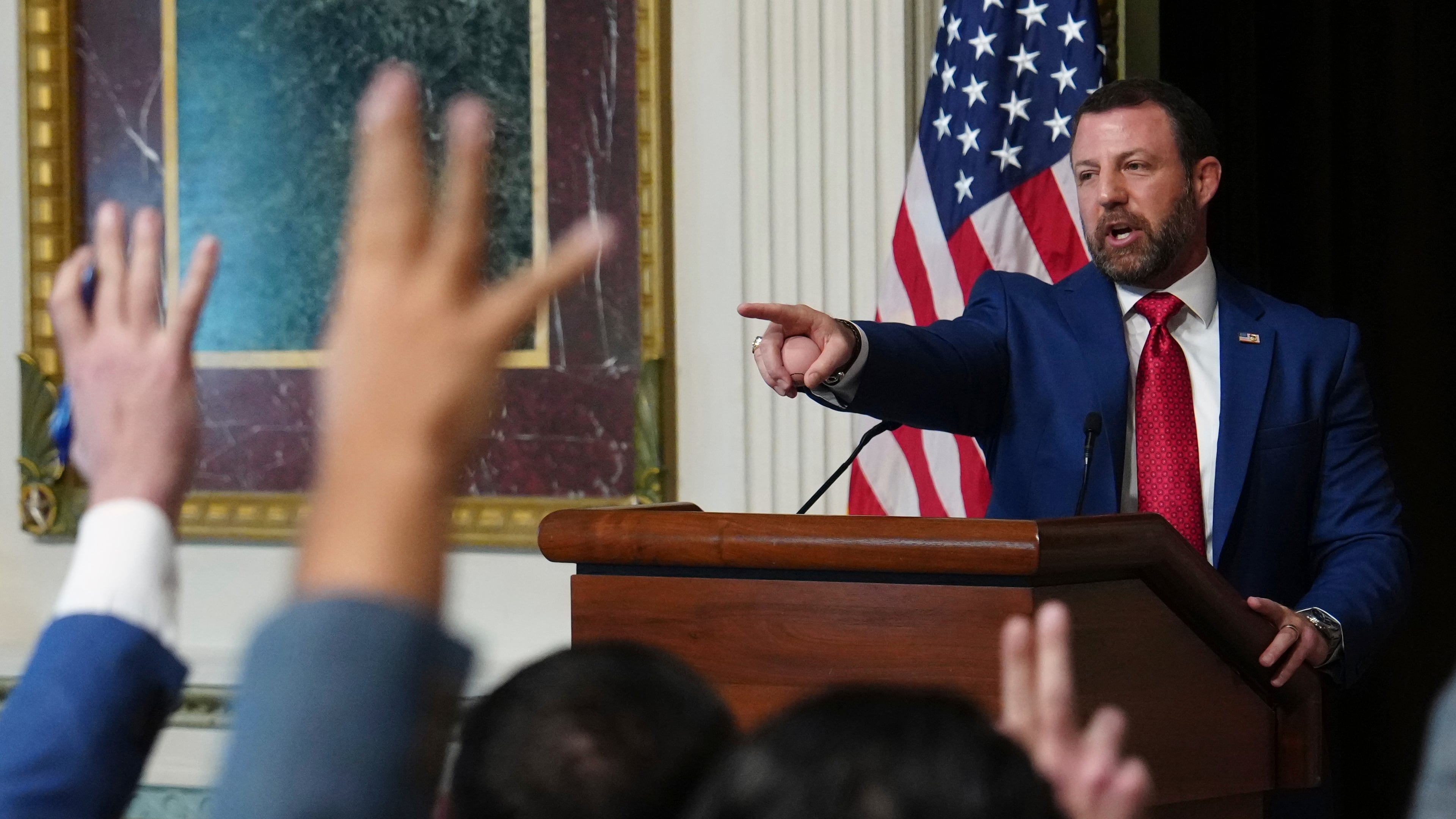 Reporters raise their hands as Homeland Security Secretary Markwayne Mullin speaks in the Indian Treaty Room at the Eisenhower Executive Office Building on the White House campus, Friday, July 17, 2026, in Washington. (AP Photo/Julia Demaree Nikhinson)