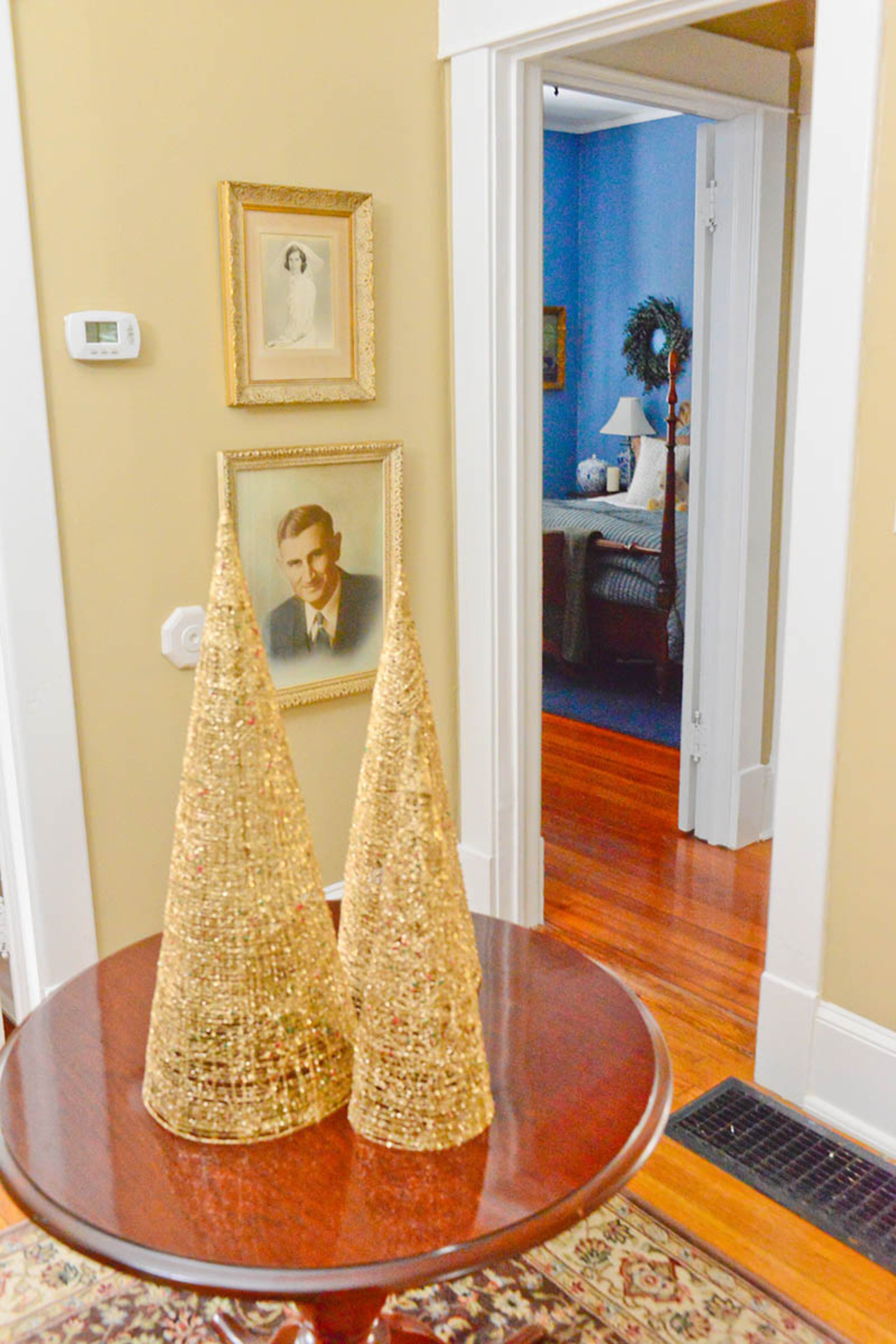 Wire Christmas trees sparkle with jewels atop a round table in the foyer. The table once stood in an hotel lobby, but Gandee gave it a new home after discovering it in an antiques market. On the wall, framed photos of Kendrick's mother and grandfather watch over the home.