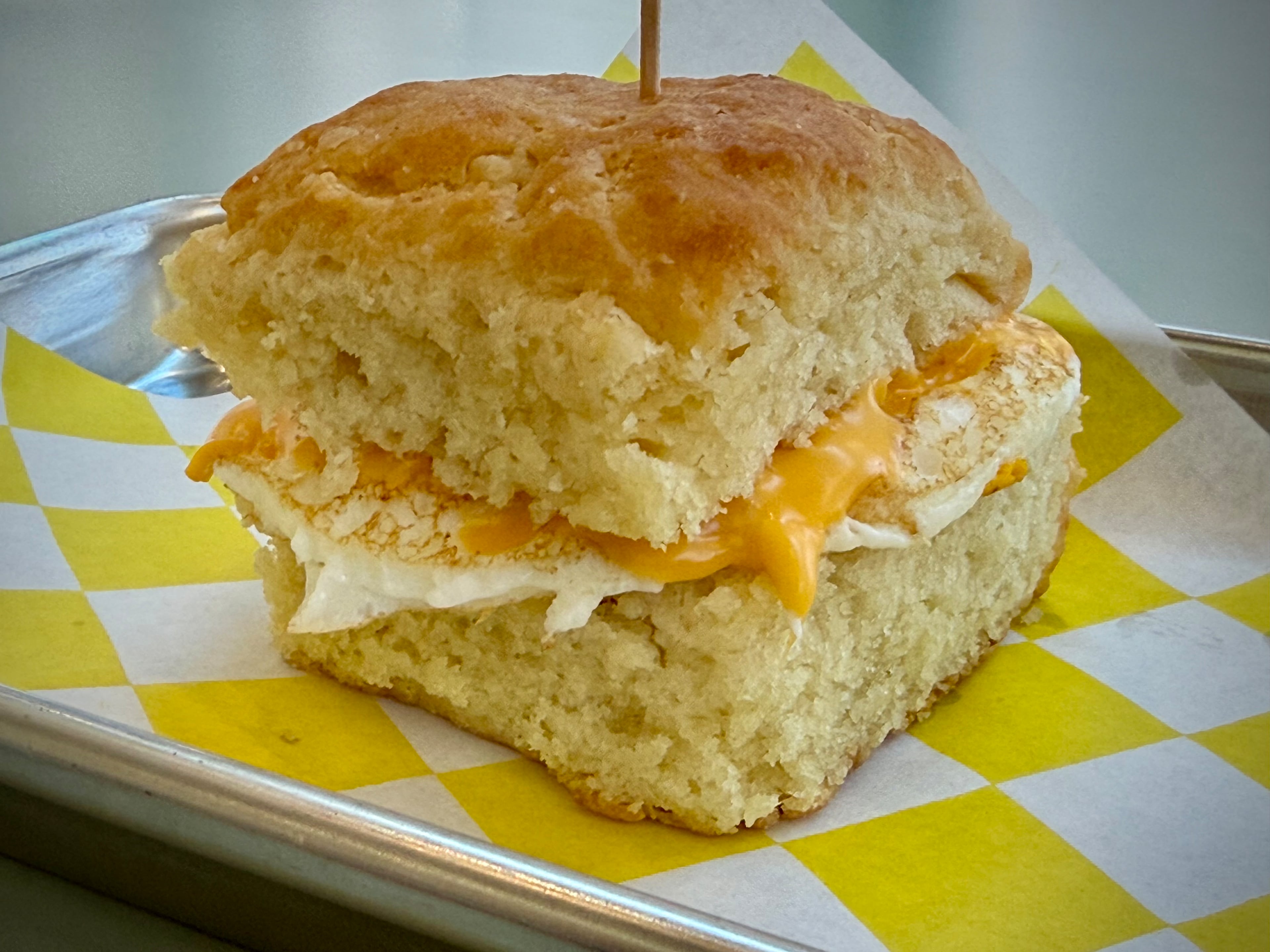 An egg and cheese breakfast sandwich on a classic buttermilk biscuit, the runaway winner in the AJC’s biscuit taste test, is served at Sugar Loaf. (Henri Hollis/AJC)