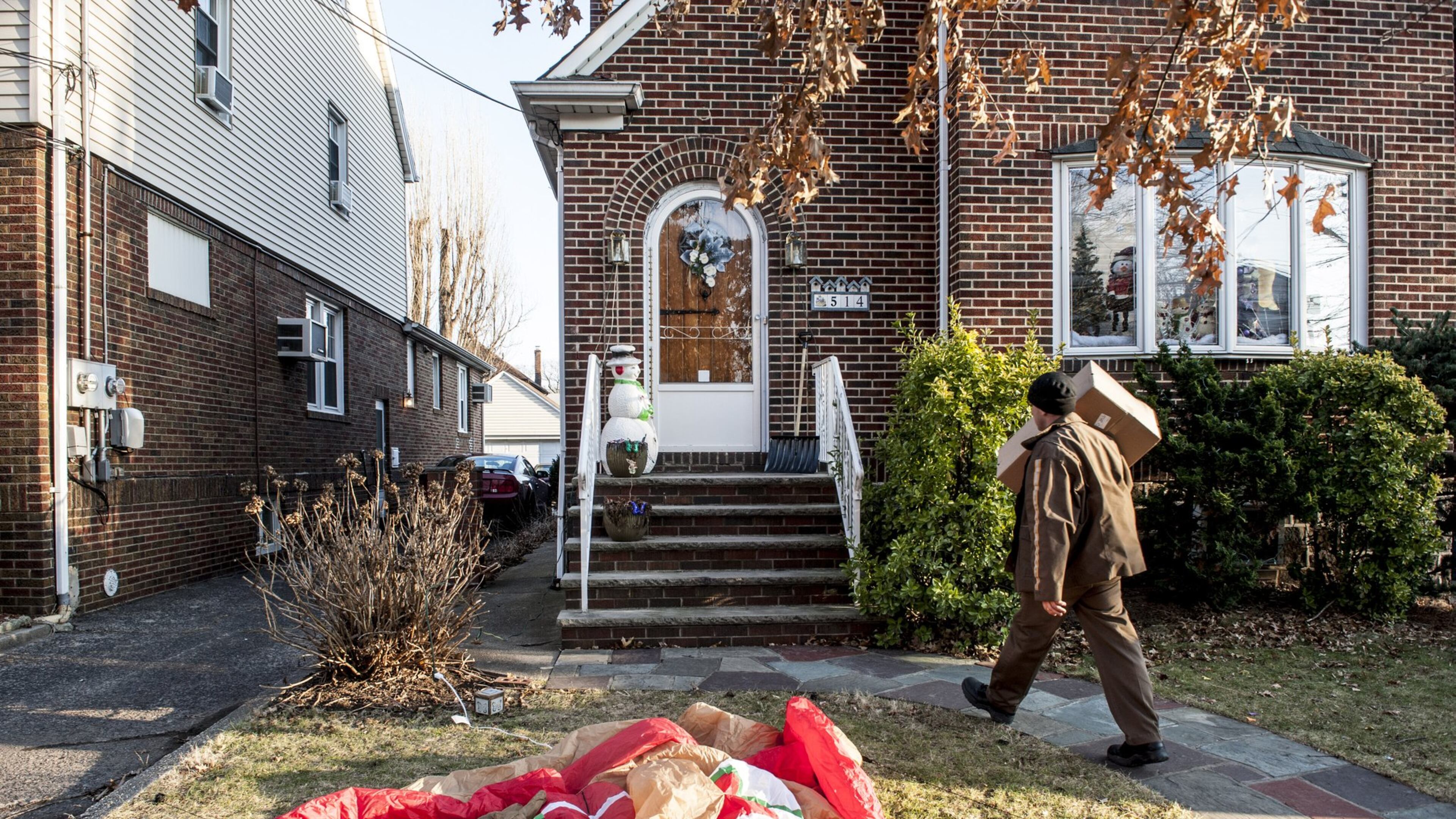 A UPS worker passes deflated Christmas decorations to deliver a package in the borough of Cliffside Park in Bergen County, N.J., Dec. 26, 2013. Across the country, some customers were left without Christmas gifts as the United Parcel Service failed to meet delivery deadlines in the face of bad weather and an unexpectedly large surge in demand.