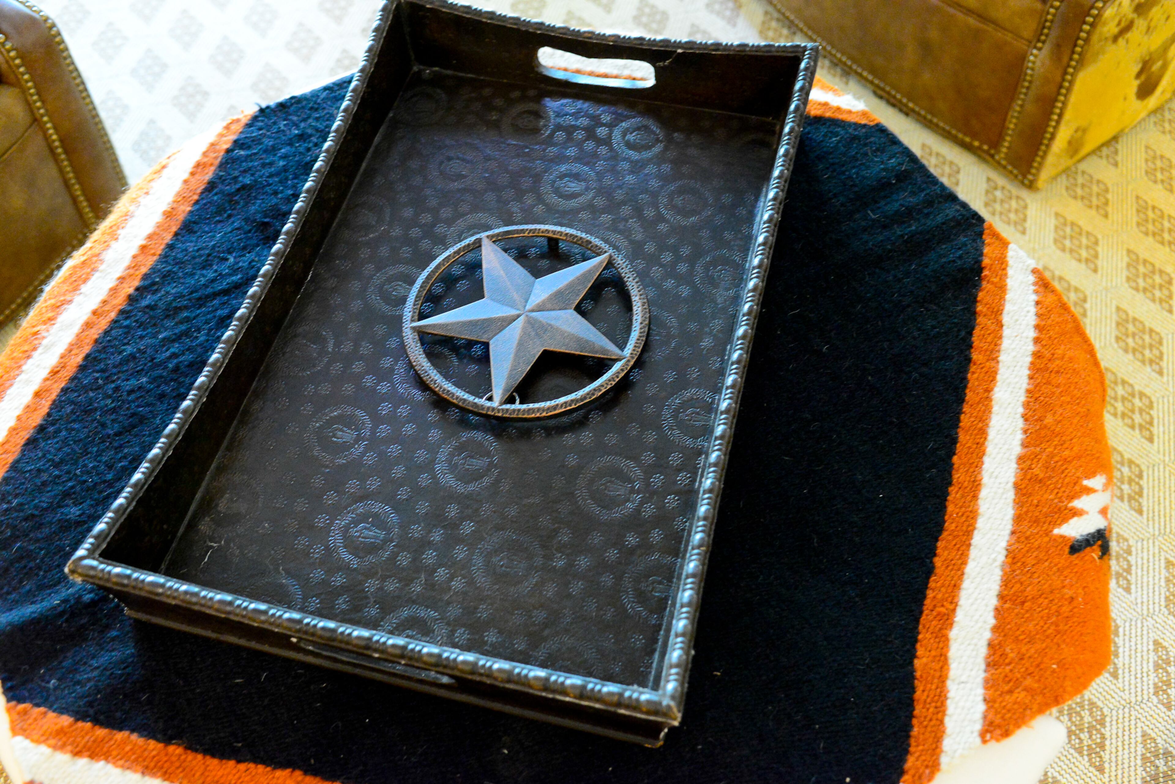 An ottoman (from AmericasMart Atlanta) is layered with a stable blanket, and a tray decorated with a star that fits with the basement's western theme.